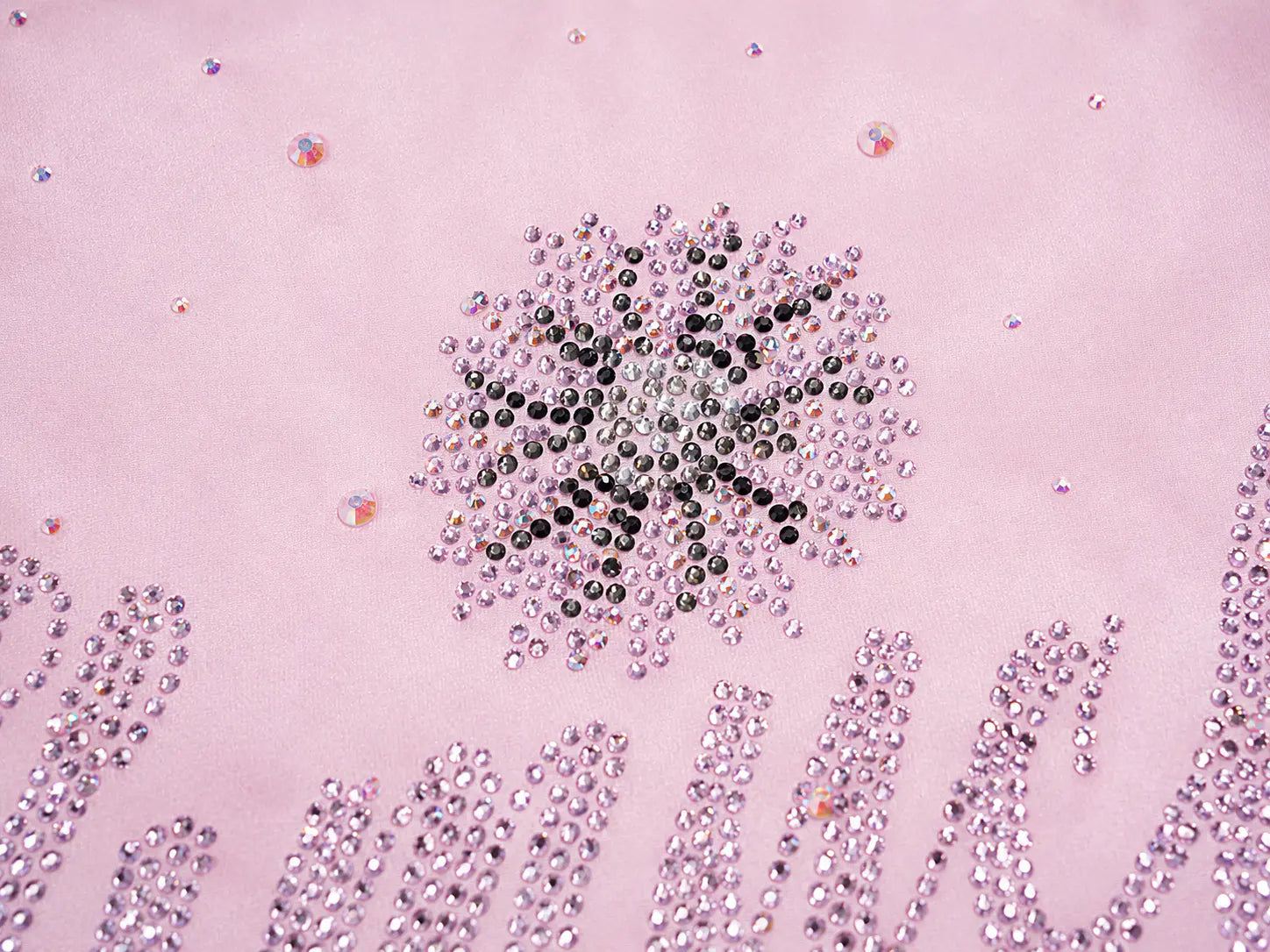 A close-up of a light pink surface decorated with rhinestones, featuring a central snowflake-like design made of black, silver, and pink rhinestones, with partial cursive lettering at the bottom. TCH Rhinestone Crystal Embellished Pink Shirt & Shorts Set