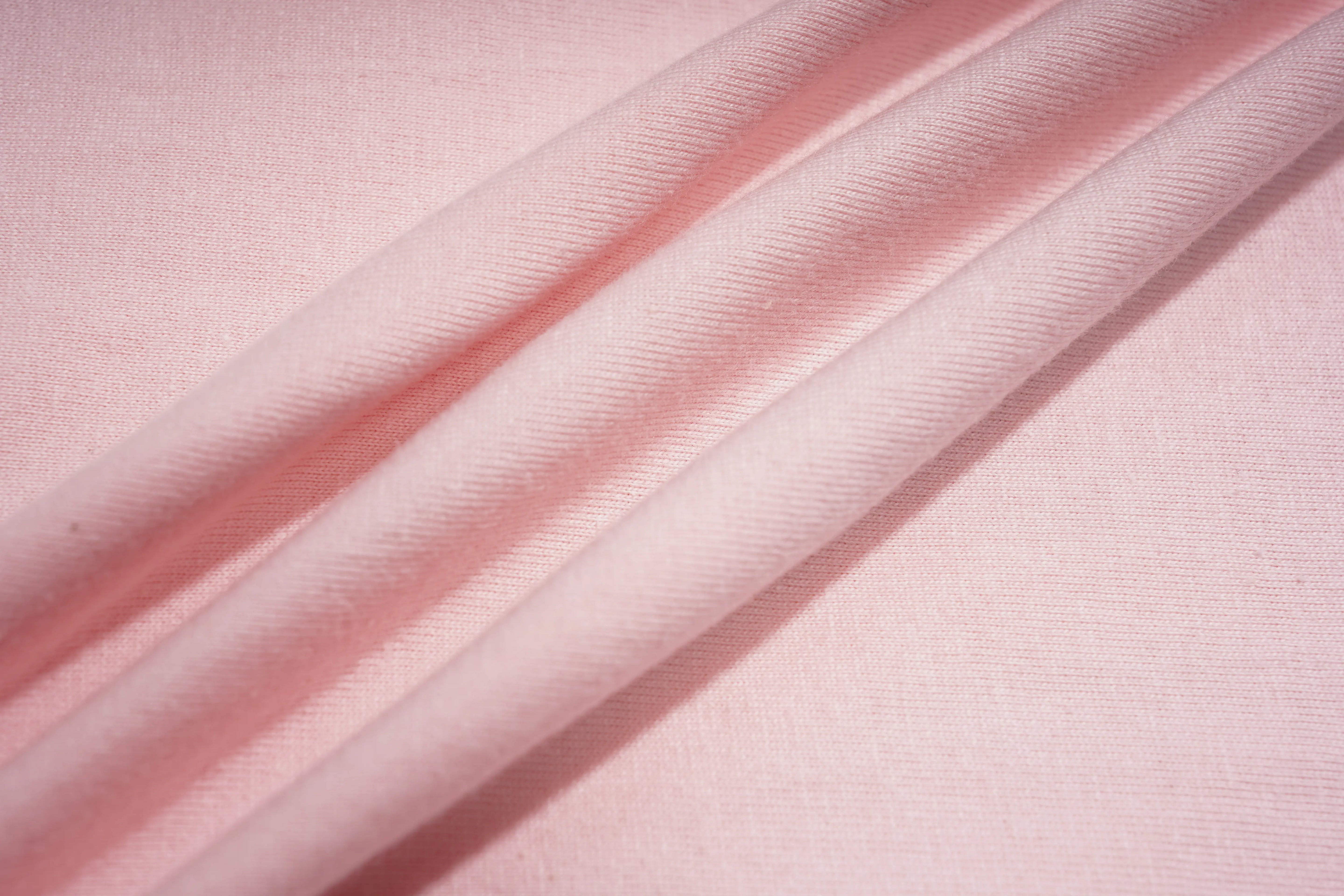 A close-up of light pink fabric with soft diagonal folds showing a fine woven texture. TCH Rhinestone Double Bow Cotton T-Shirt