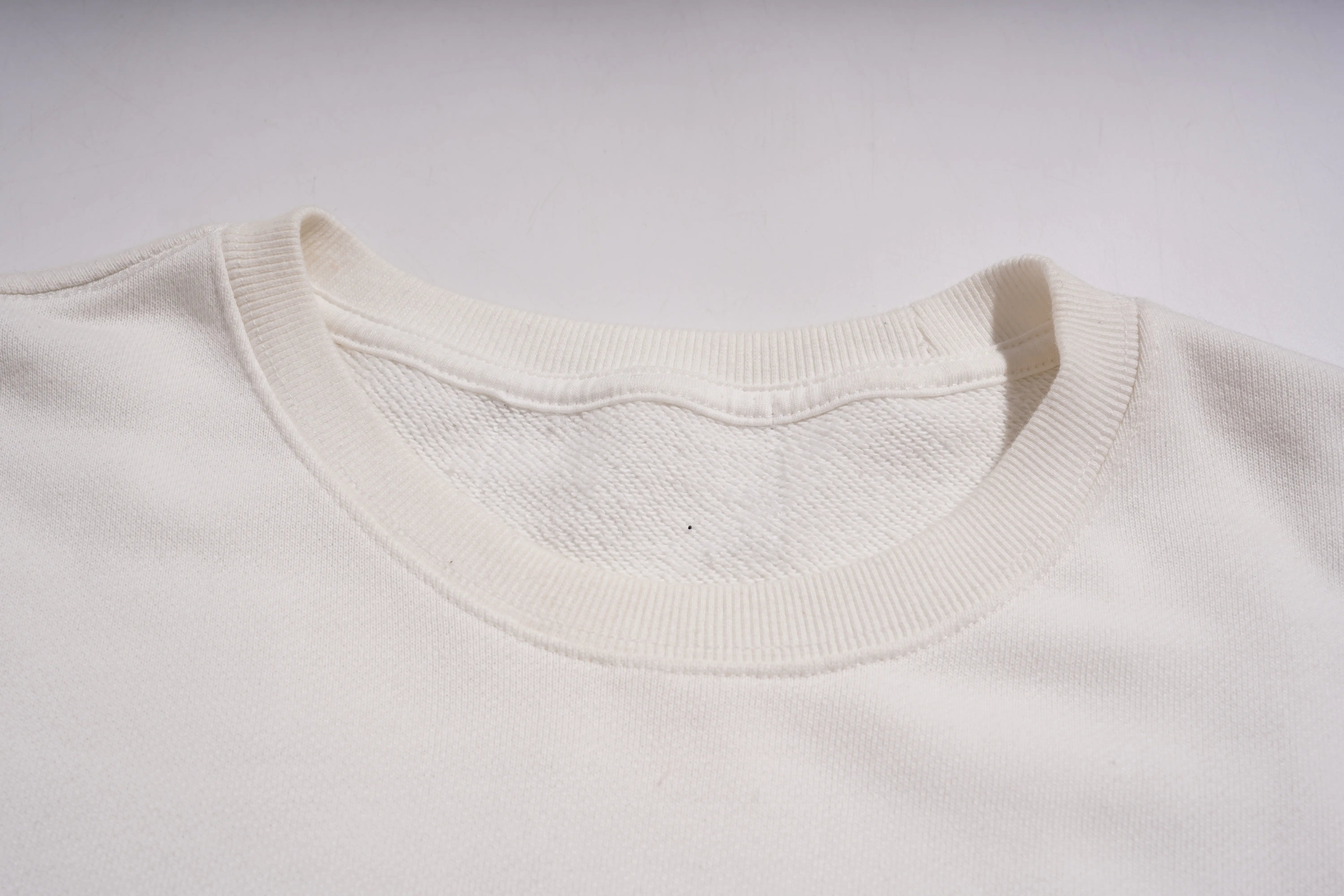 Close-up of a white sweater collar on a light gray background
