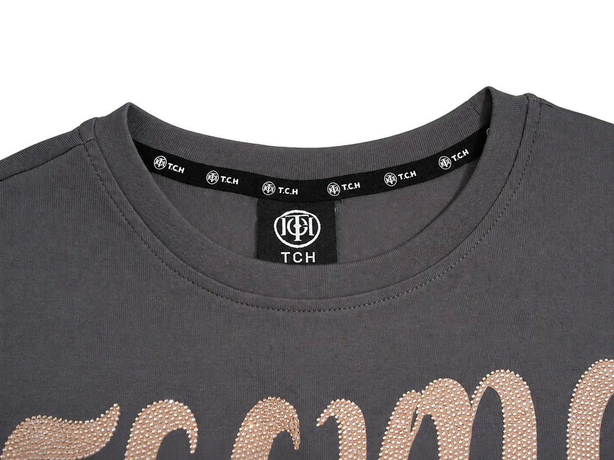 Close-up of a dark gray crewneck t-shirt featuring a large rose gold rhinestone script across the chest and a black neck label with TCH branding. TCH Rhinestone Fantasy Unicorn Graphic Long Sleeve T-Shirt