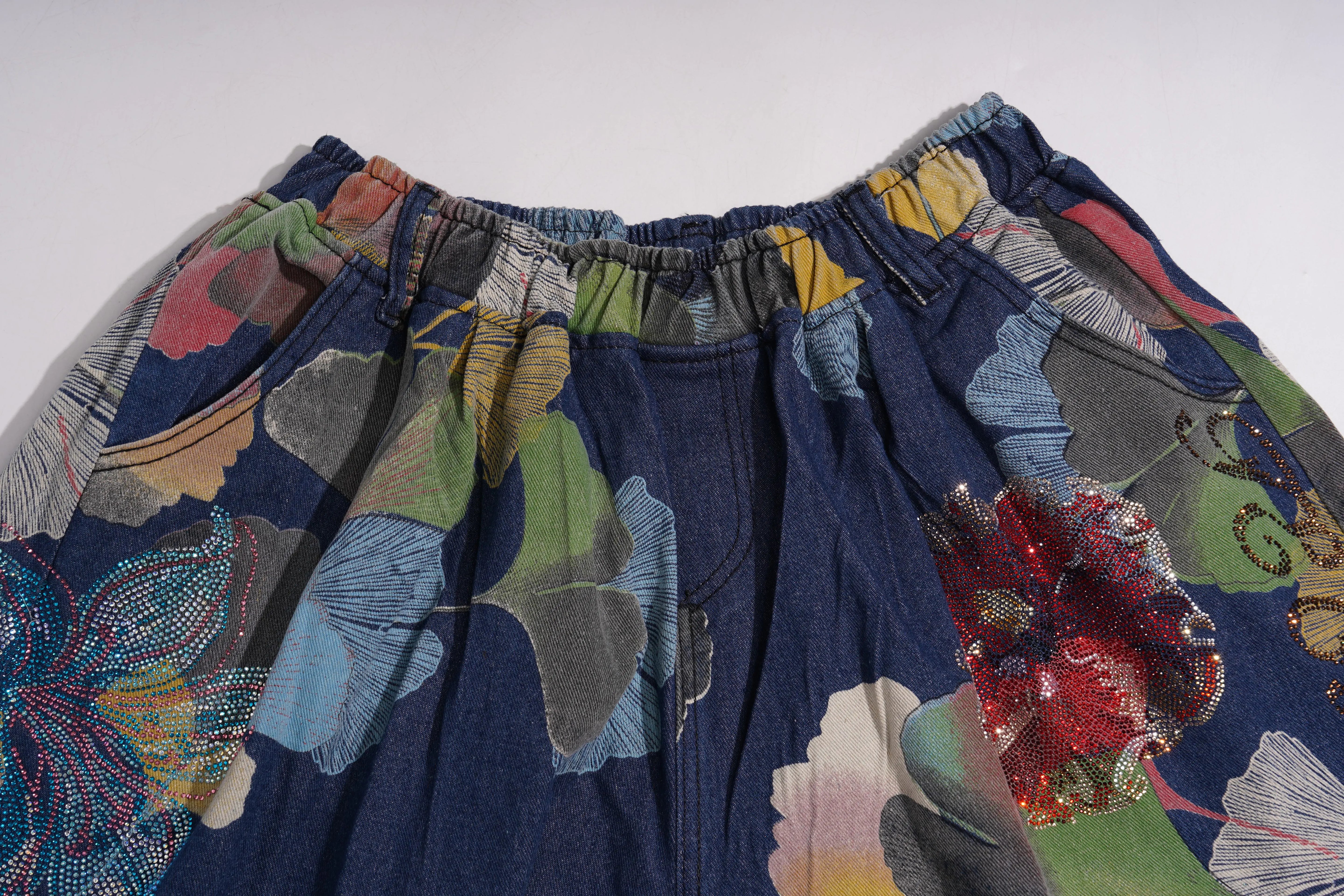 Colorful floral-patterned fabric with a focus on texture and design. TCH Rhinestone Floral Ginkgo Print Denim Shorts