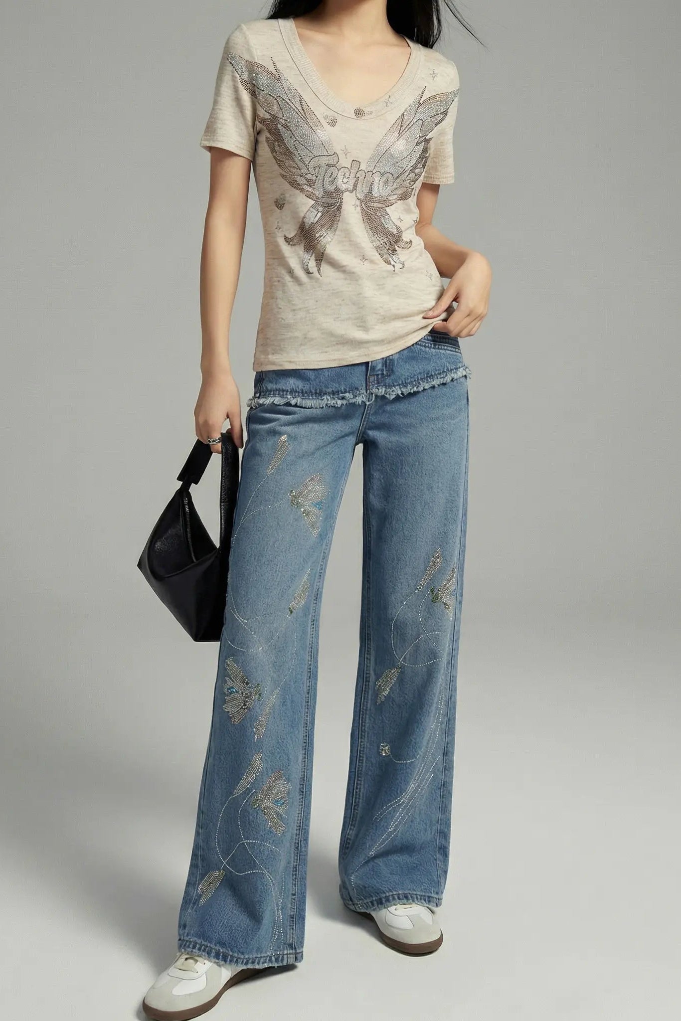 Person wearing a graphic t-shirt and blue jeans on a gray background, TCH Rhinestone Floral Wide-Leg Blue Jeans