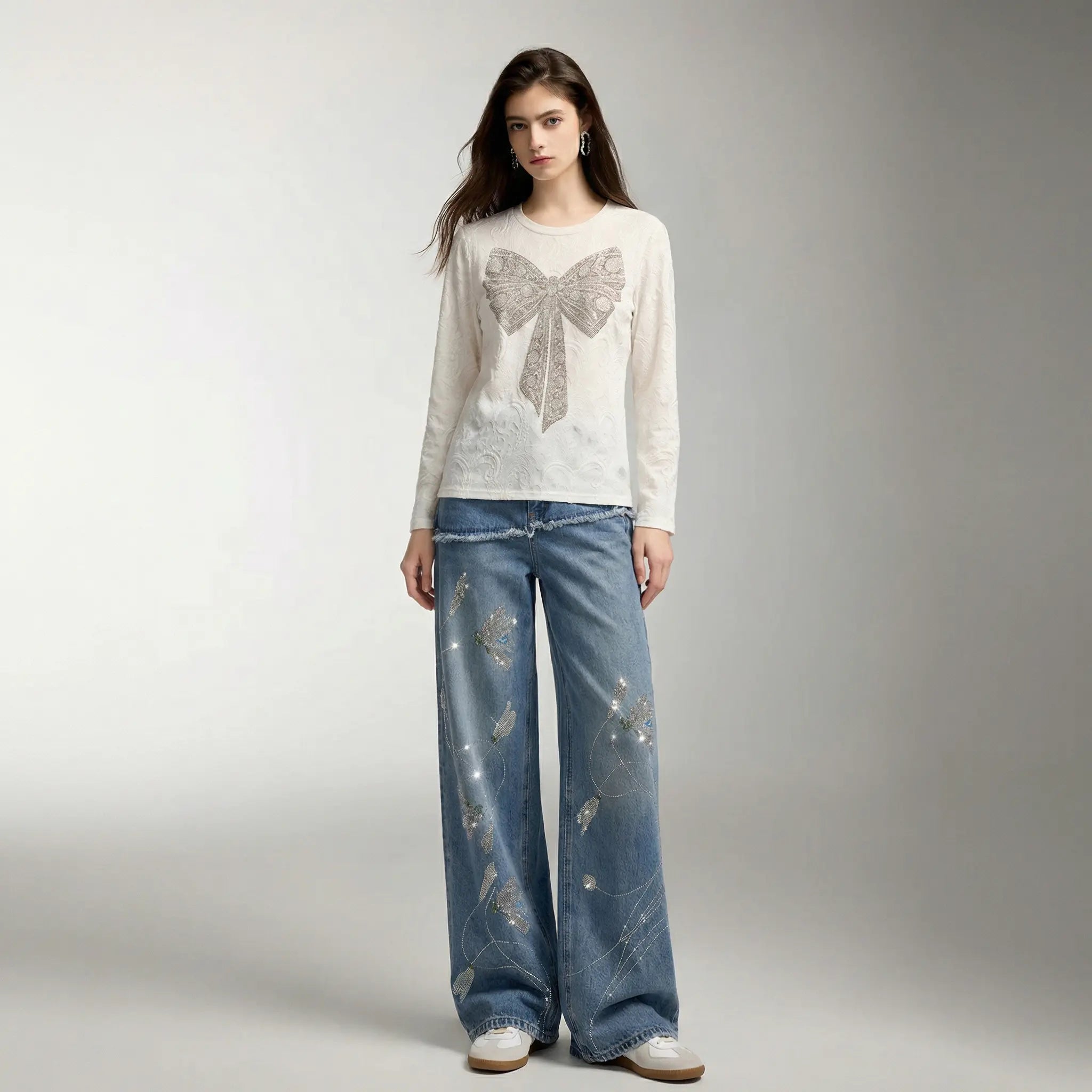 Woman wearing a white blouse with a bow design and blue jeans on a gray background, TCH Rhinestone Floral Wide-Leg Blue Jeans
