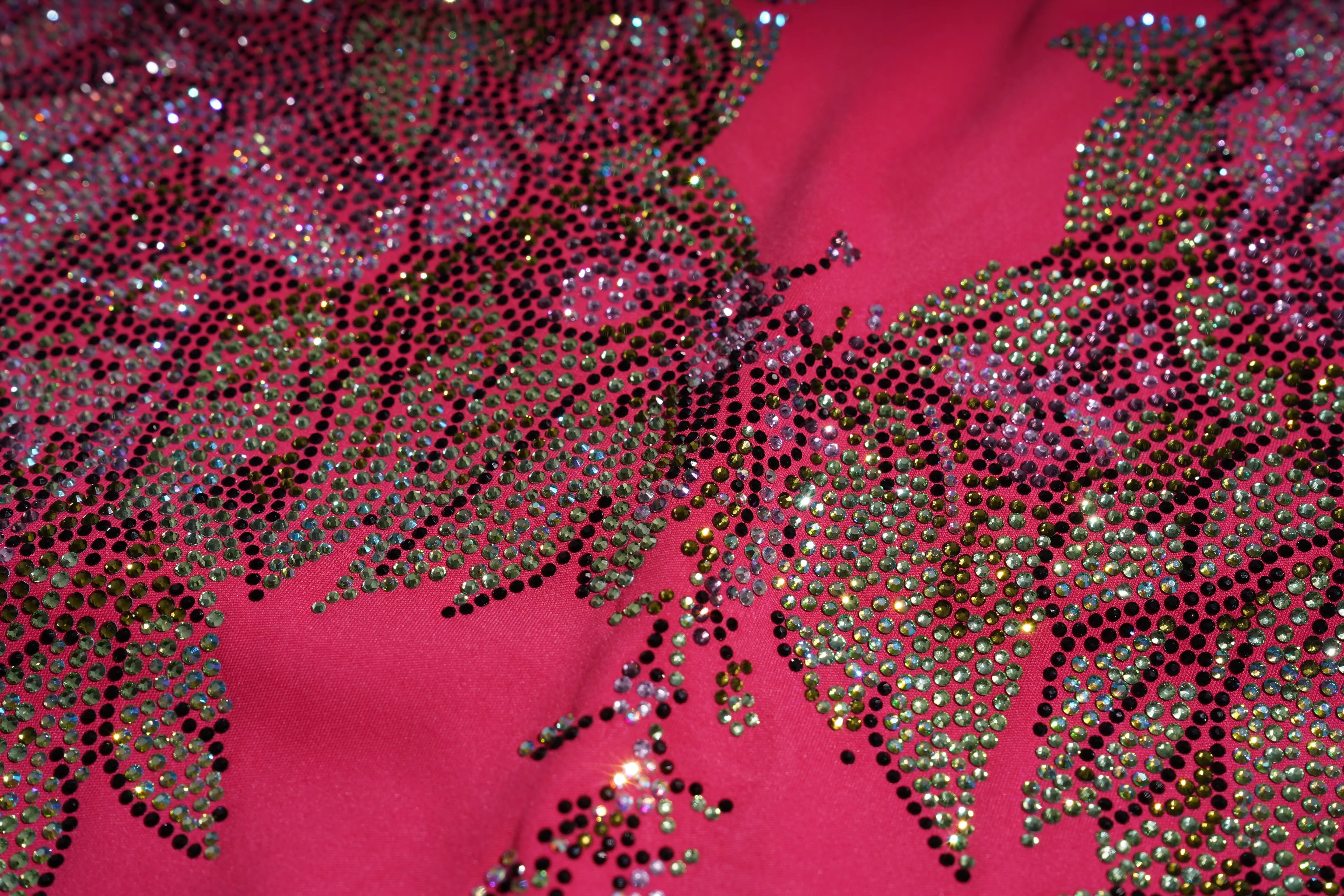 Close-up of a pink fabric with gold leaf patterns and rhinestones. TCH Rhinestone Floral Wing Yoga Jumpsuit-