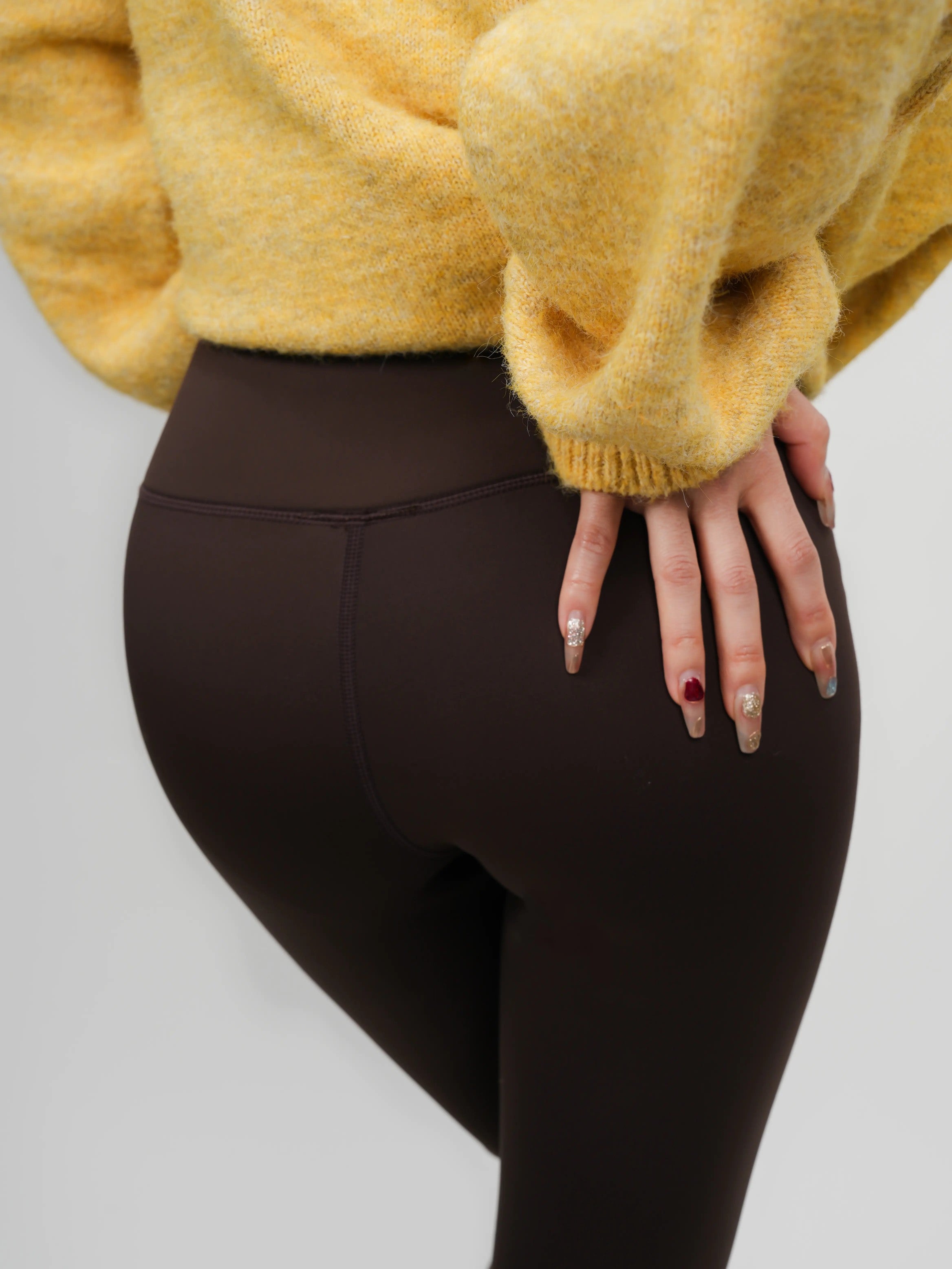 Person wearing brown leggings and a yellow sweater on a light gray background, TCH Rhinestone Golden Wings Black High-Waist Leggings