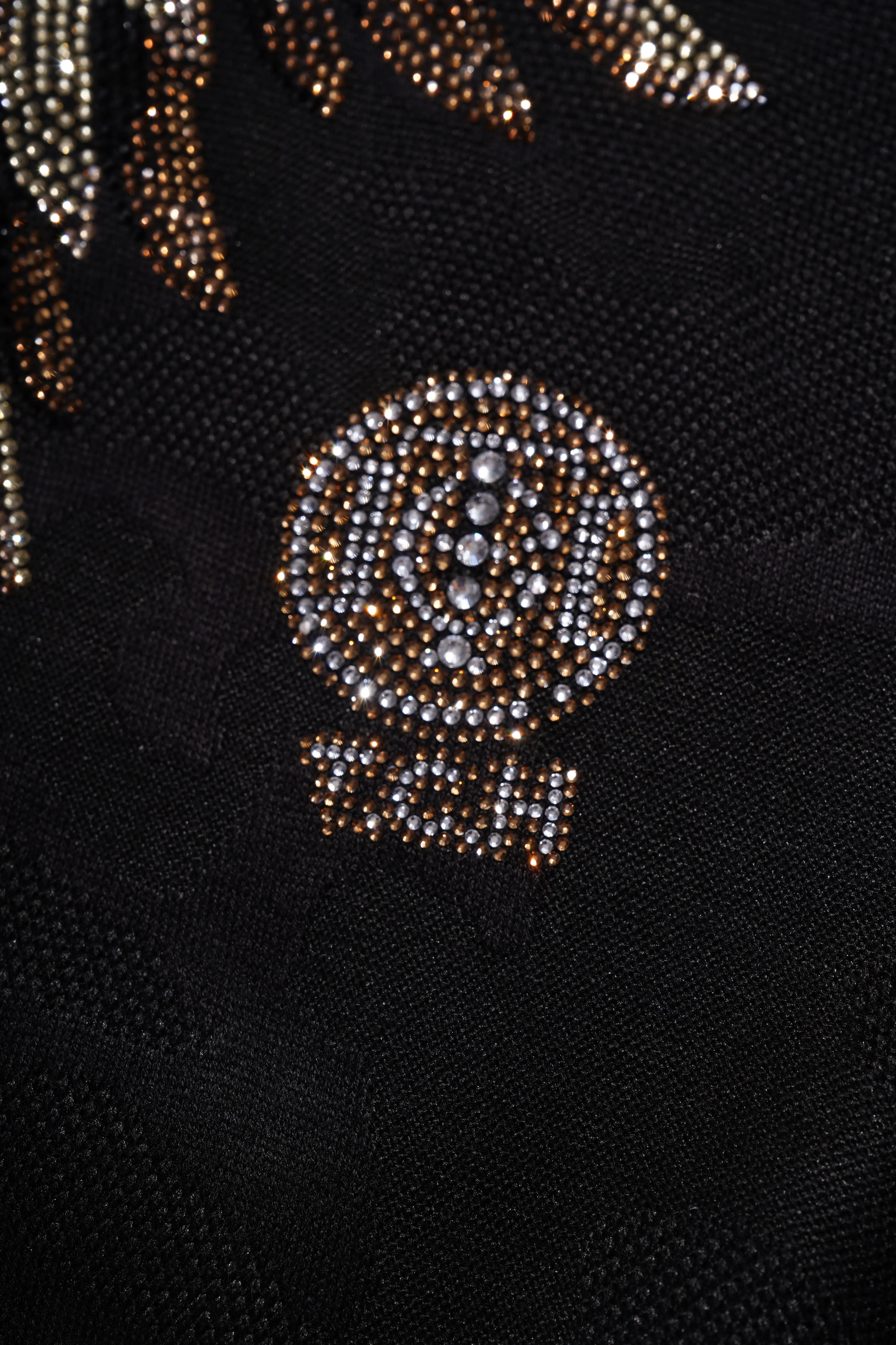 Close-up of a black fabric with gold and silver embellishments on a dark background, TCH Rhinestone Golden Wings Sweatshirt