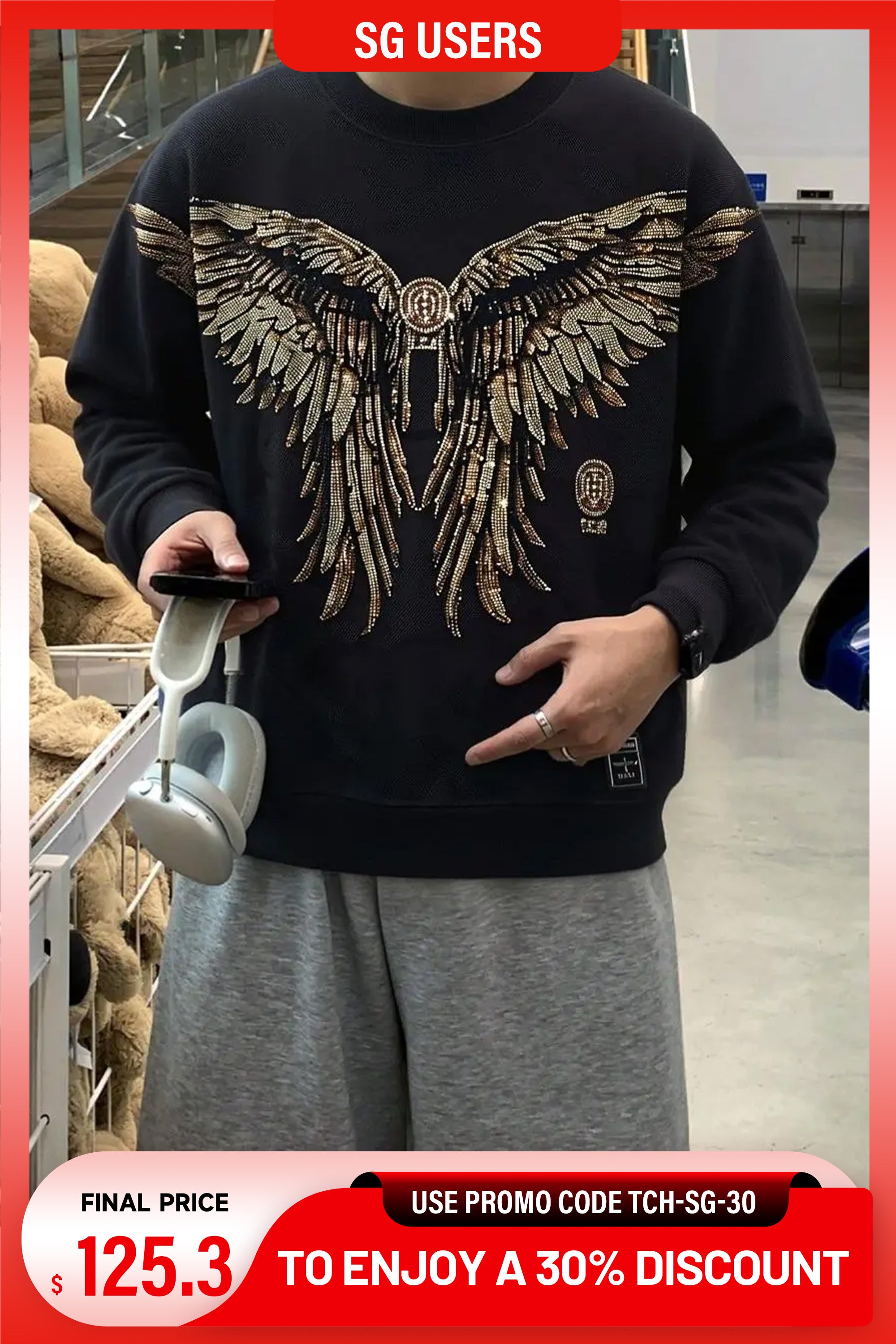 Person wearing a black sweatshirt with a large winged design, standing in a store. TCH Rhinestone Golden Wings Sweatshirt