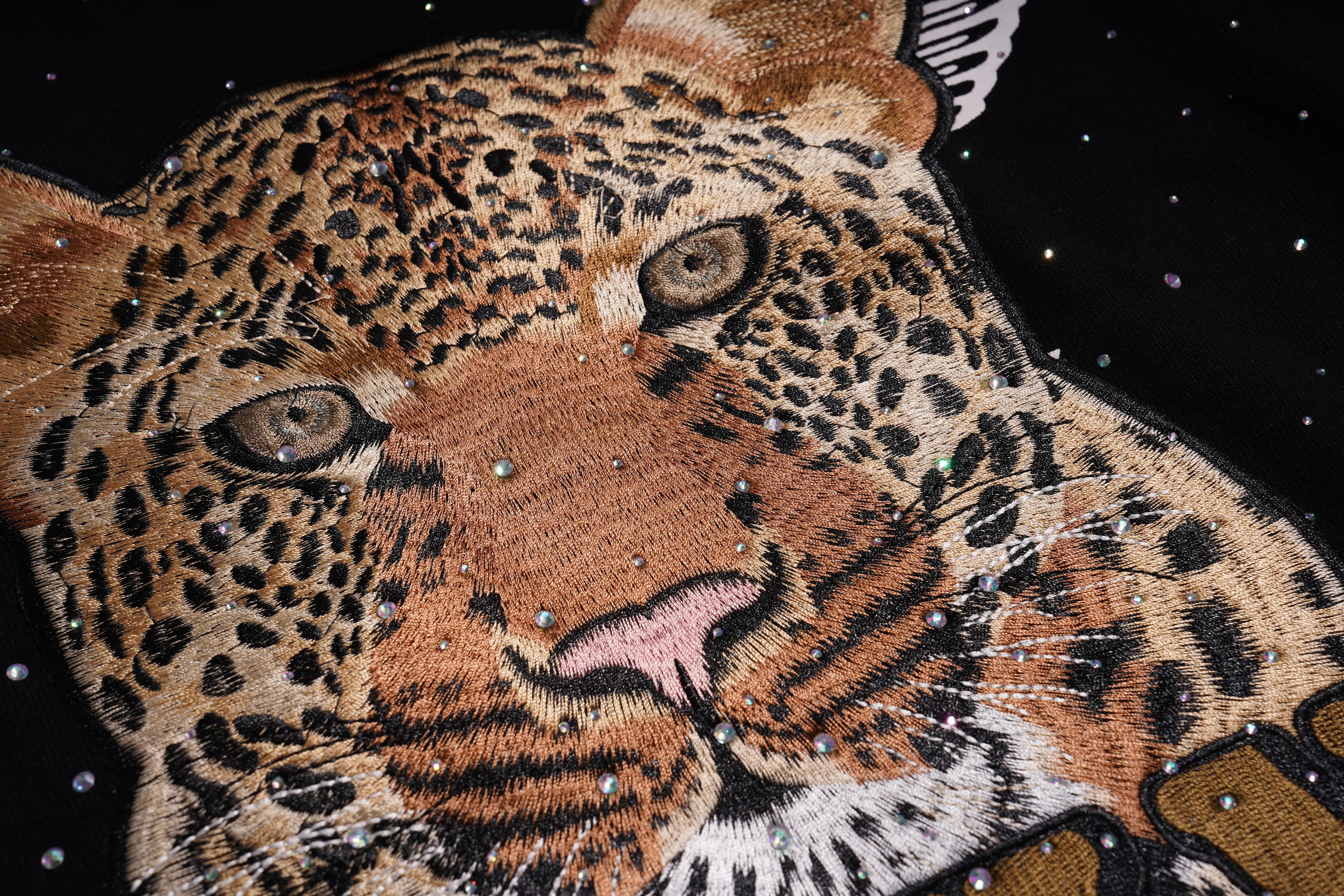 Embroidered patch of a leopard face with rhinestone embellishments on a black background, TCH Rhinestone Gradient Star Leopard Sweatshirt