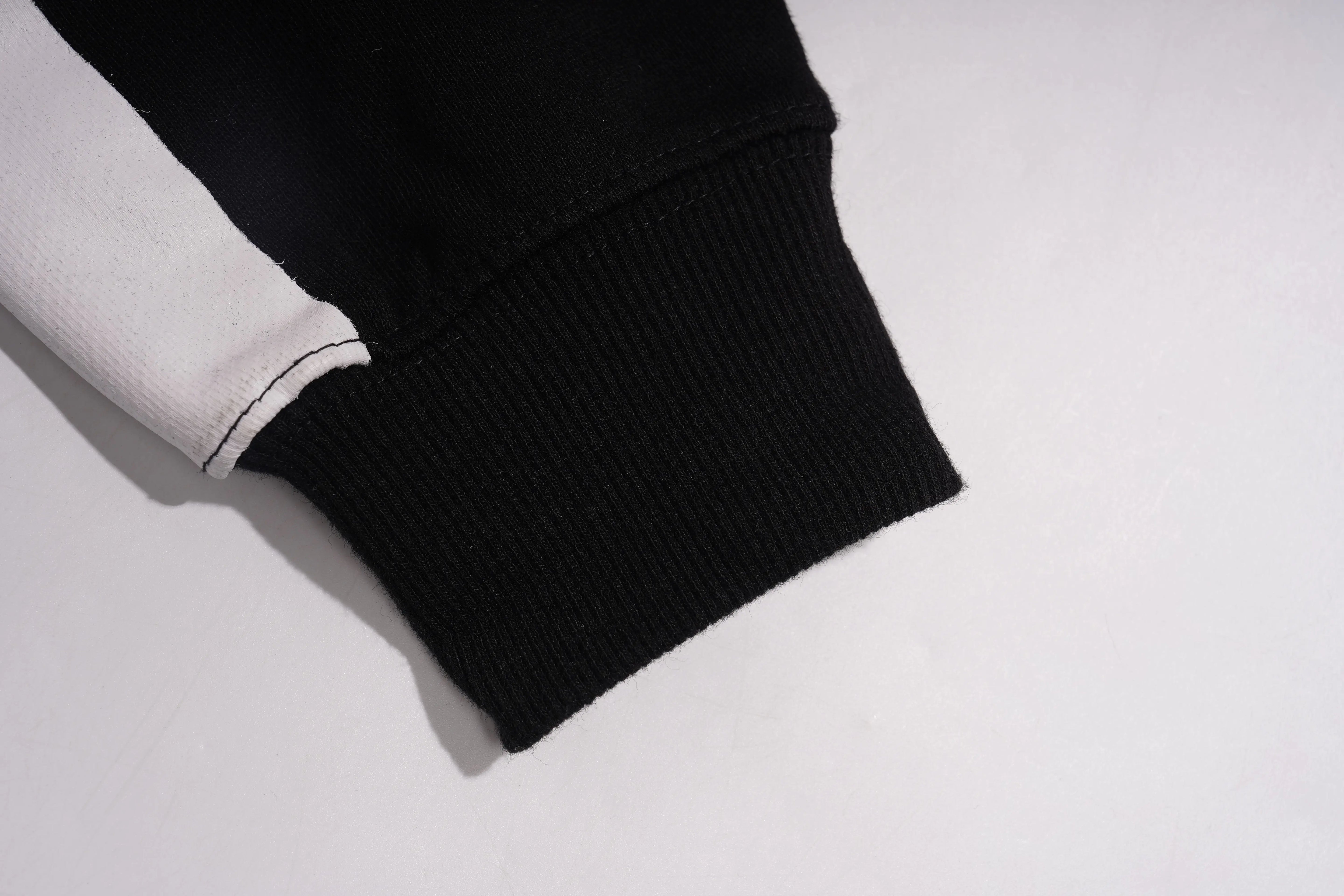 Close-up of a black sleeve with white trim on a light gray background, TCH Rhinestone Hello Kitty BOYLONDON Sweatshirt