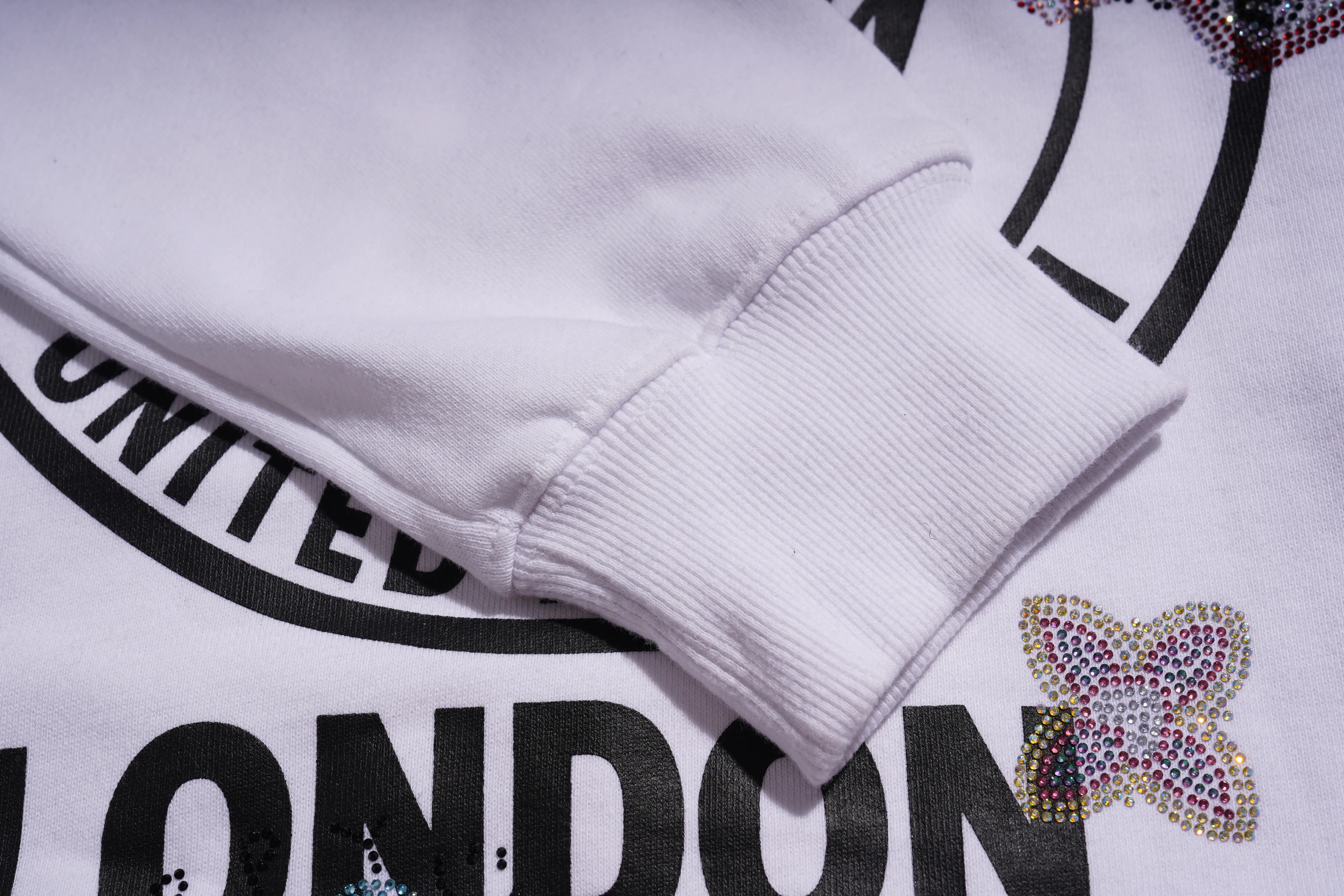 Close-up of a white sweatshirt with 'UNITED LONDON' text and decorative elements.