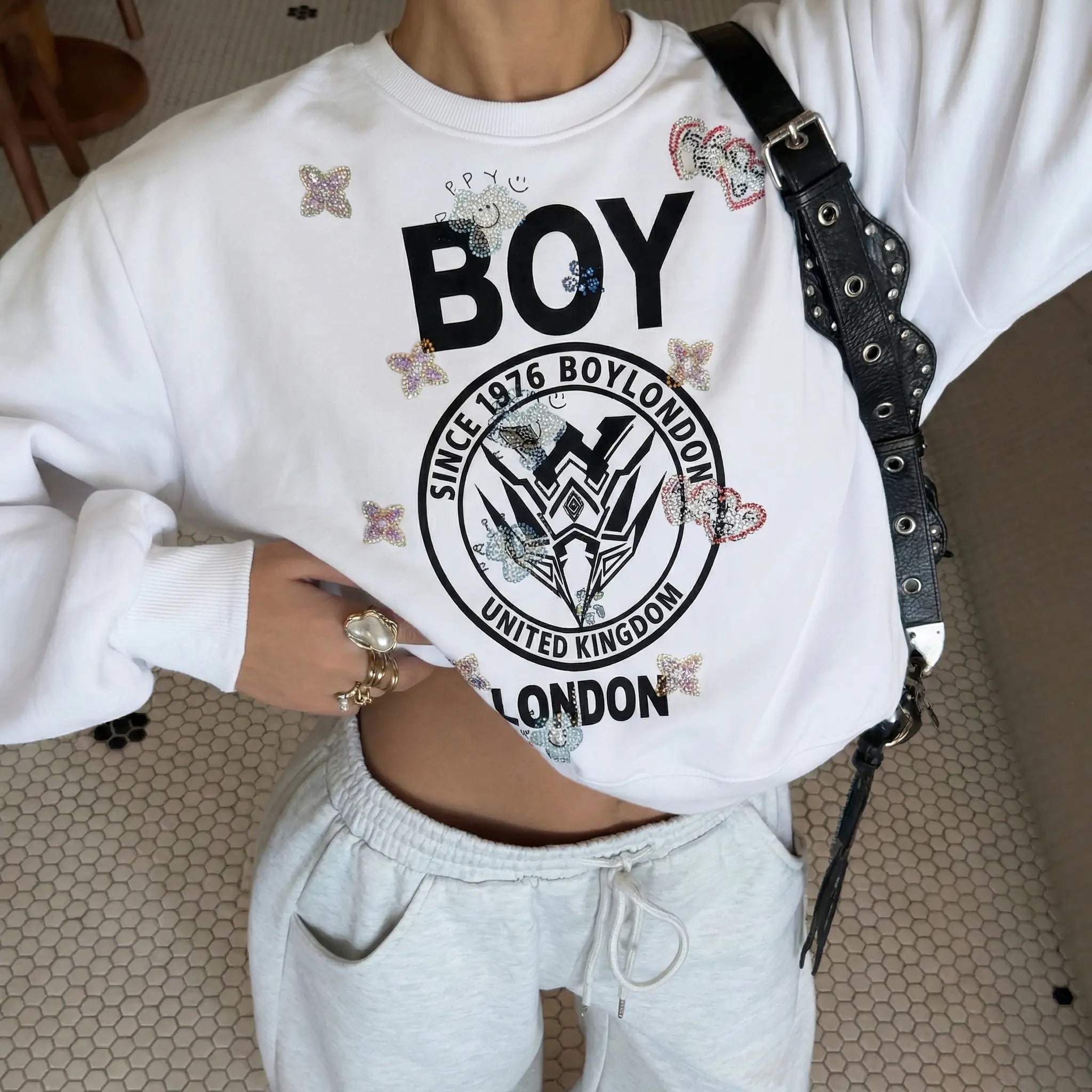 White sweatshirt with 'BOY LONDON' logo and text, worn by a person indoors. TCH Rhinestone Logo Print Crew Neck Sweatshirt