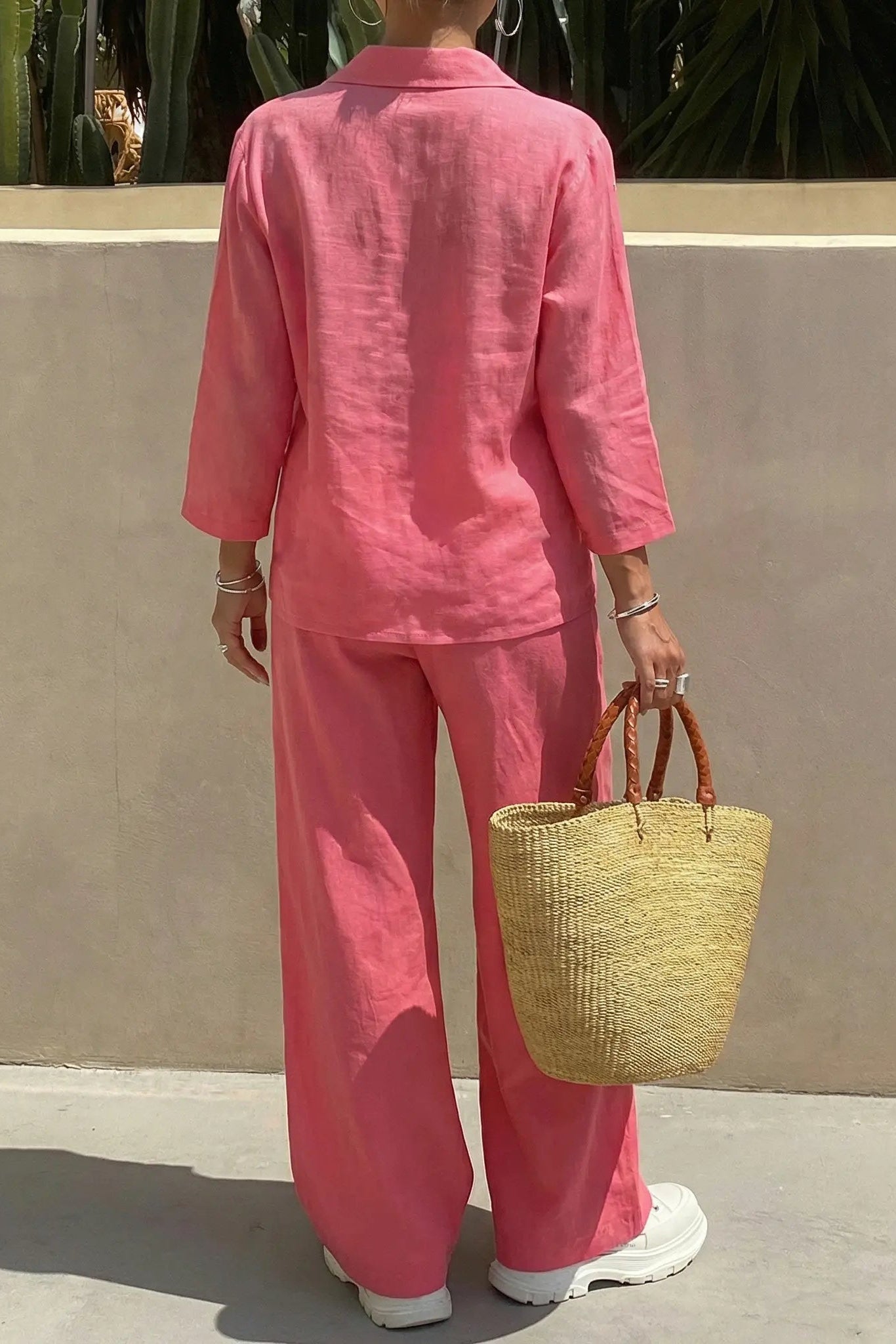 Person wearing a pink outfit holding a straw bag against a beige wall. TCH Rhinestone Love Lucky Pig Set