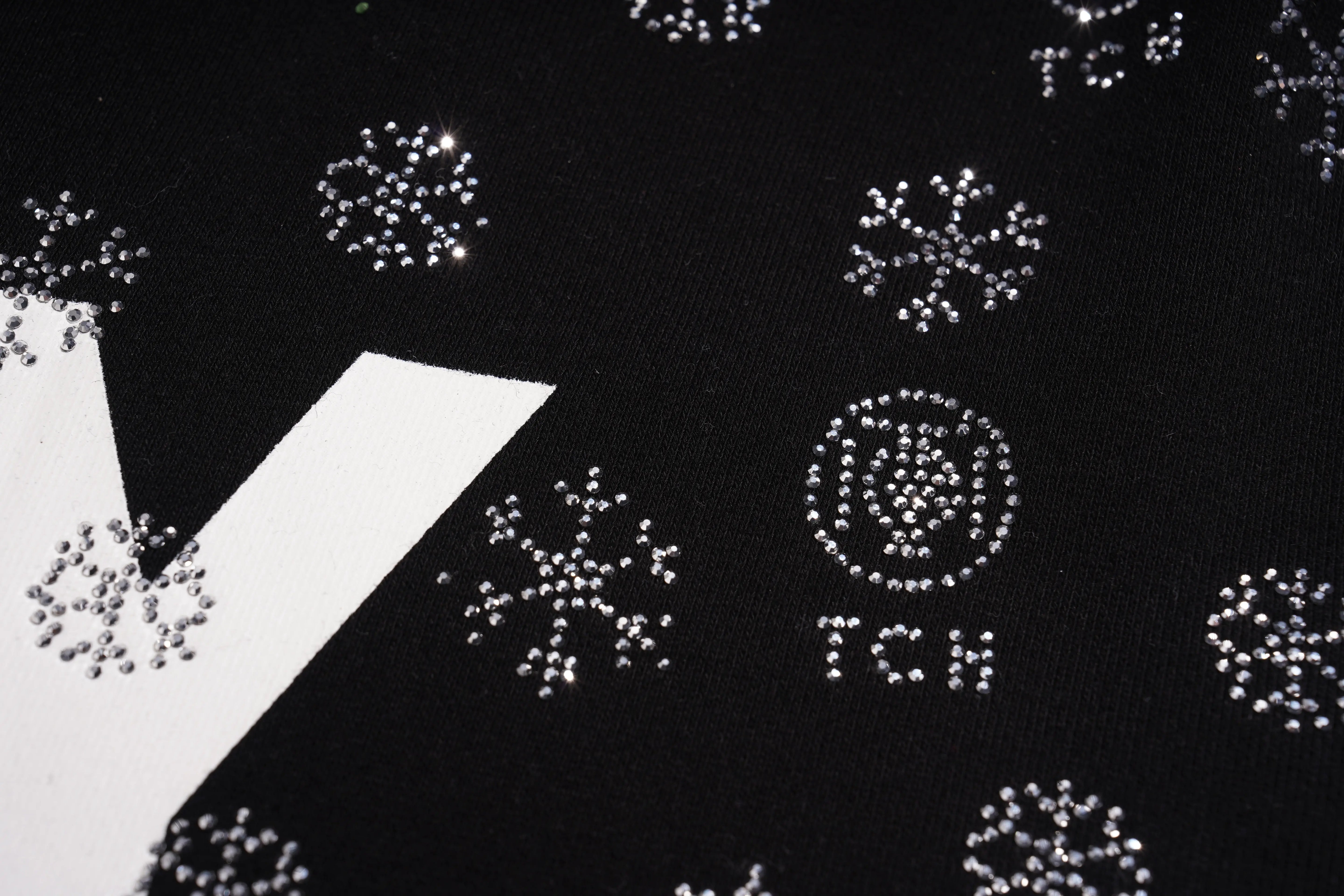 Close-up of decorative elements on a black background with 'Yves Saint Laurent' branding. TCH Rhinestone Mech Logo Crew Neck Sweatshirt