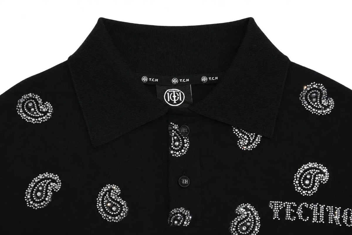 Close-up of a black polo shirt with silver rhinestone paisley patterns and 'TECHNO' text on the chest, featuring a collar and button placket. TCH Rhinestone Paisley Pattern Long Sleeve Polo Shirt