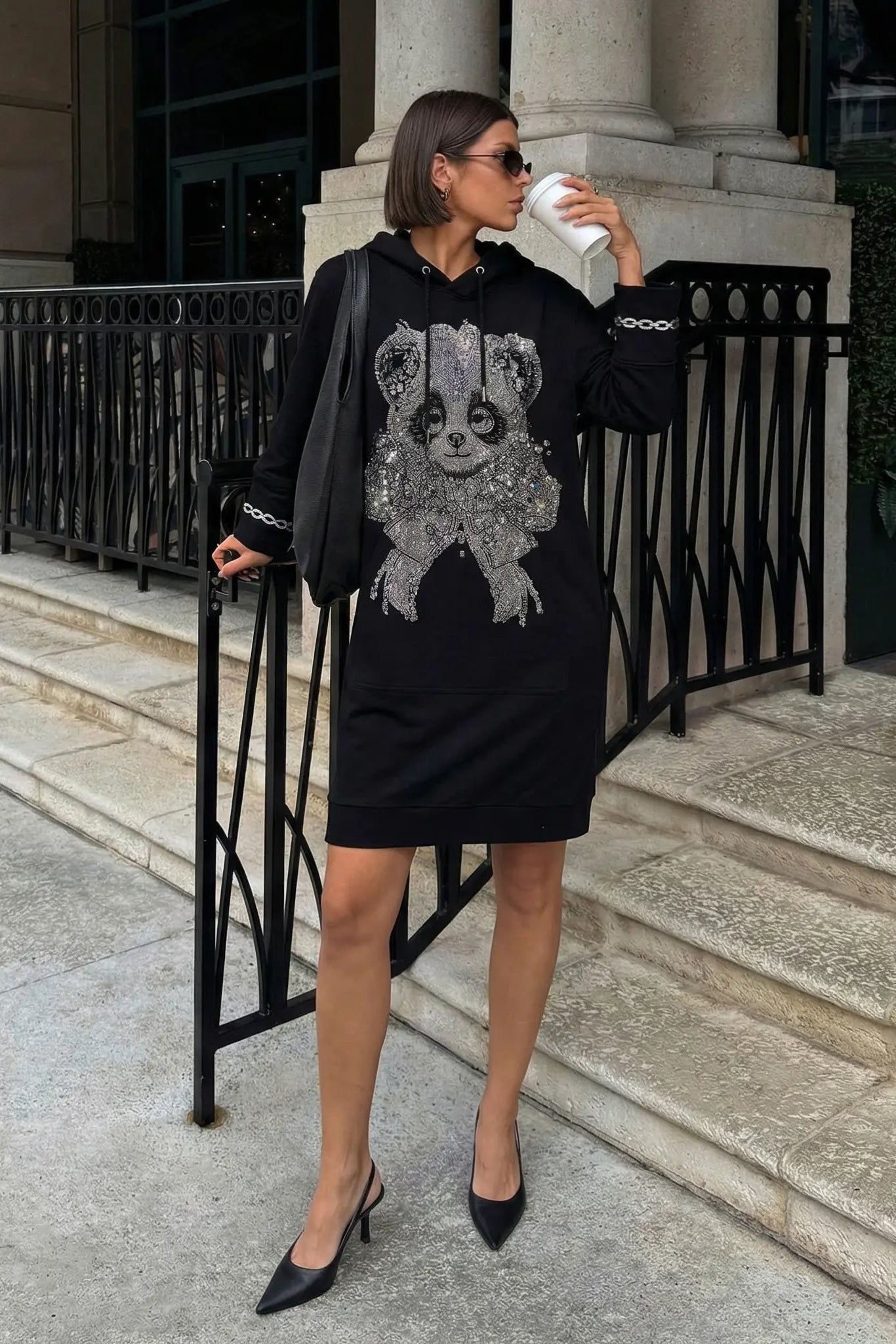 Woman wearing a black dress with a panda design, standing on steps outside a building. TCH Rhinestone Panda Bow Dress