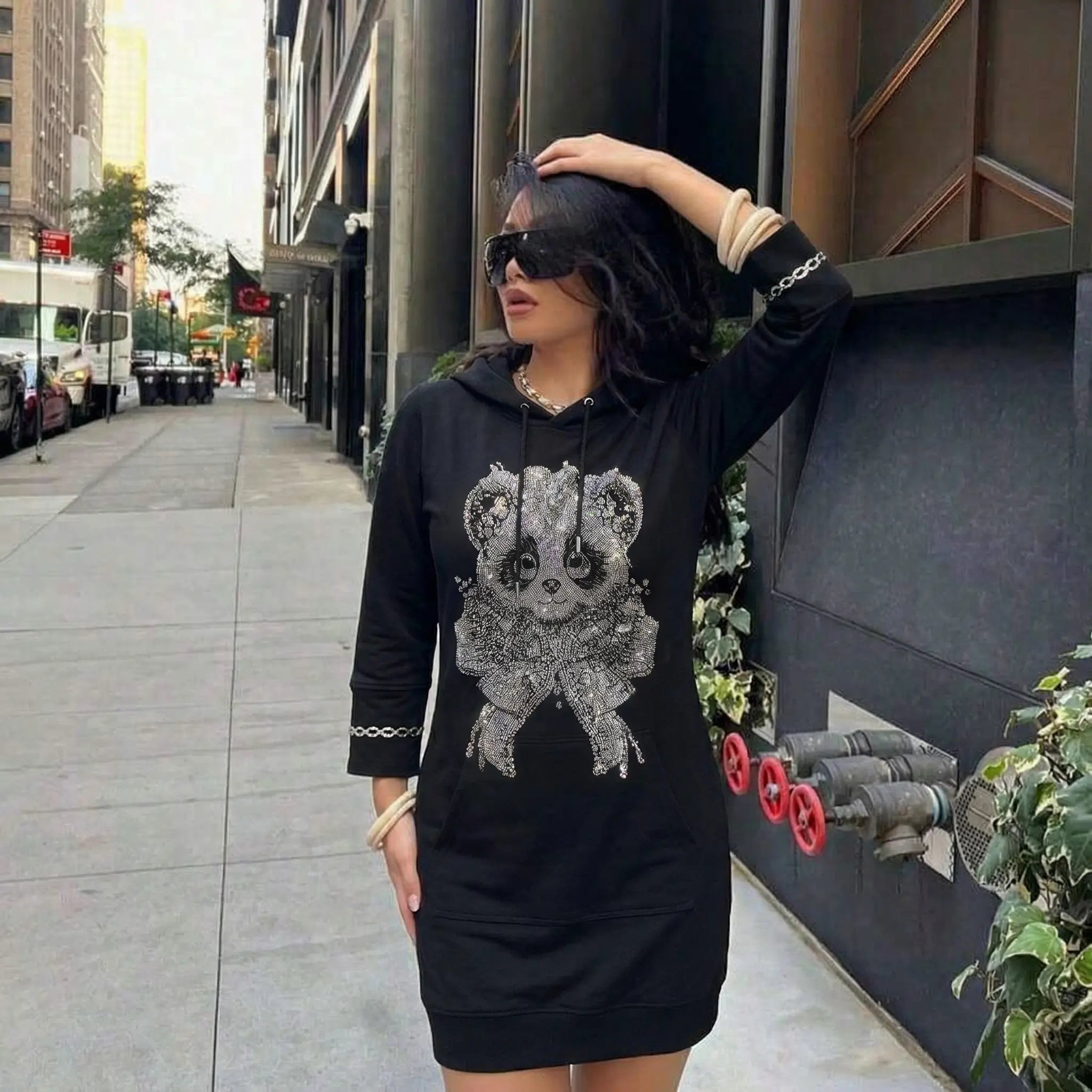 Woman wearing a black hoodie with a sequin panda design on a city street. TCH Rhinestone Panda Bow Dress