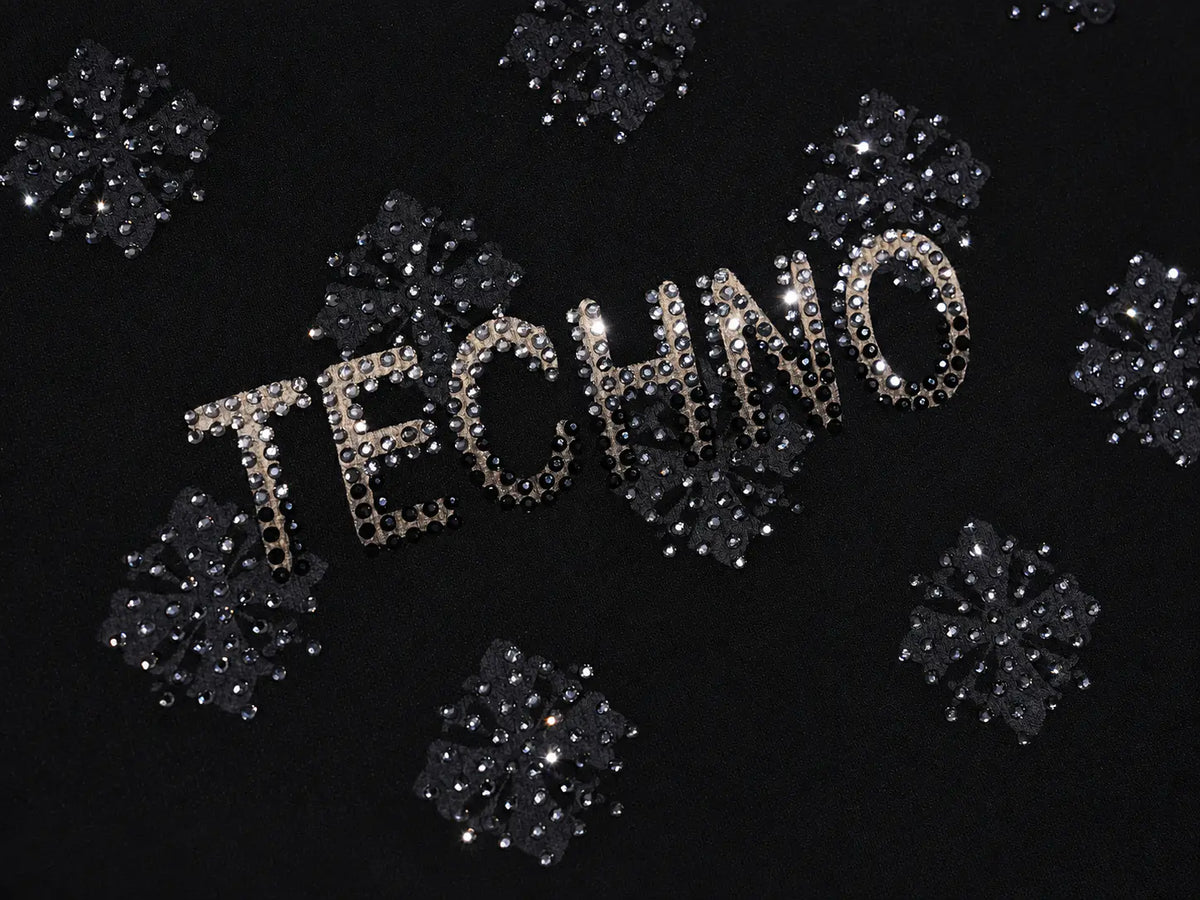 The word 'TECHNO' spelled out in sparkling silver rhinestones, surrounded by matching silver crystal snowflake embellishments on a black background. TCH Rhinestone Pattern Long Sleeve Top