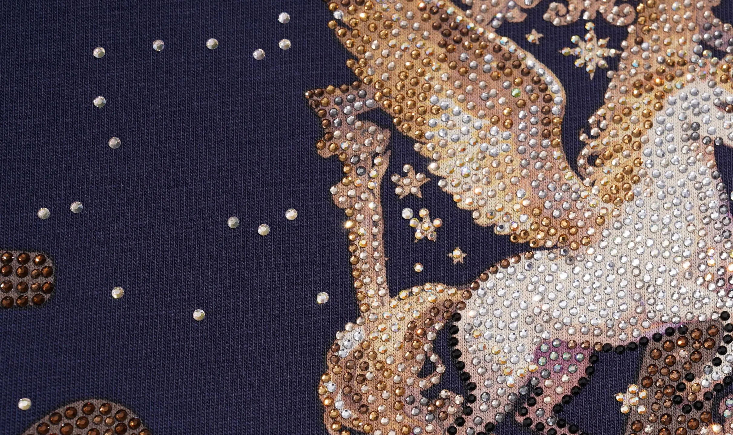 Close-up of a navy blue fabric with a large decorative illustration in metallic gold, champagne, and white tones, accented with scattered rhinestones. TCH Rhinestone Pegasus Wing Graphic Navy Blue T-Shirt