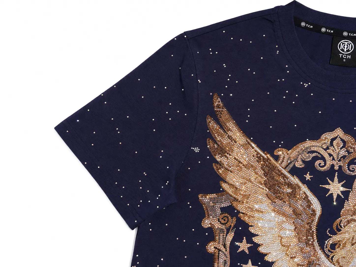 A close-up of a navy blue short-sleeve T-shirt with a large gold wing graphic and star details on the front, featuring a small white star print all over the fabric. The brand label 'TCH' is visible inside the collar. TCH Rhinestone Pegasus Wing Graphic Navy Blue T-Shirt