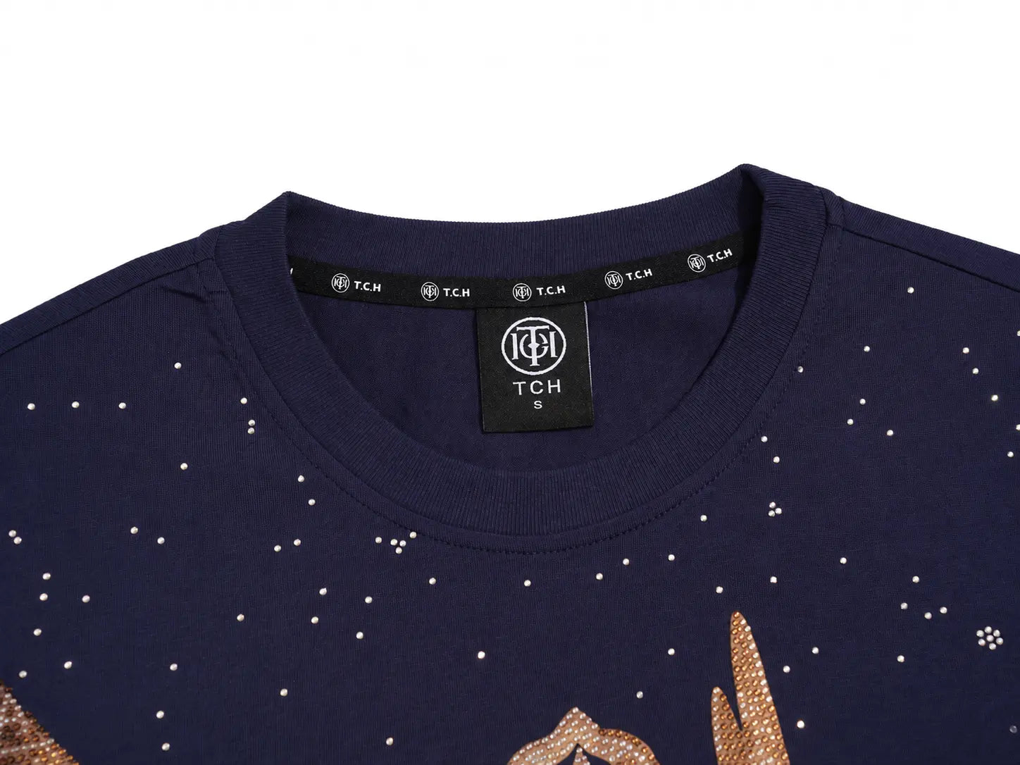 Close-up of a navy blue crewneck sweatshirt with rhinestone star details and a gold-toned graphic at the bottom, featuring a black neck label with TCH branding. TCH Rhinestone Pegasus Wing Graphic Navy Blue T-Shirt
