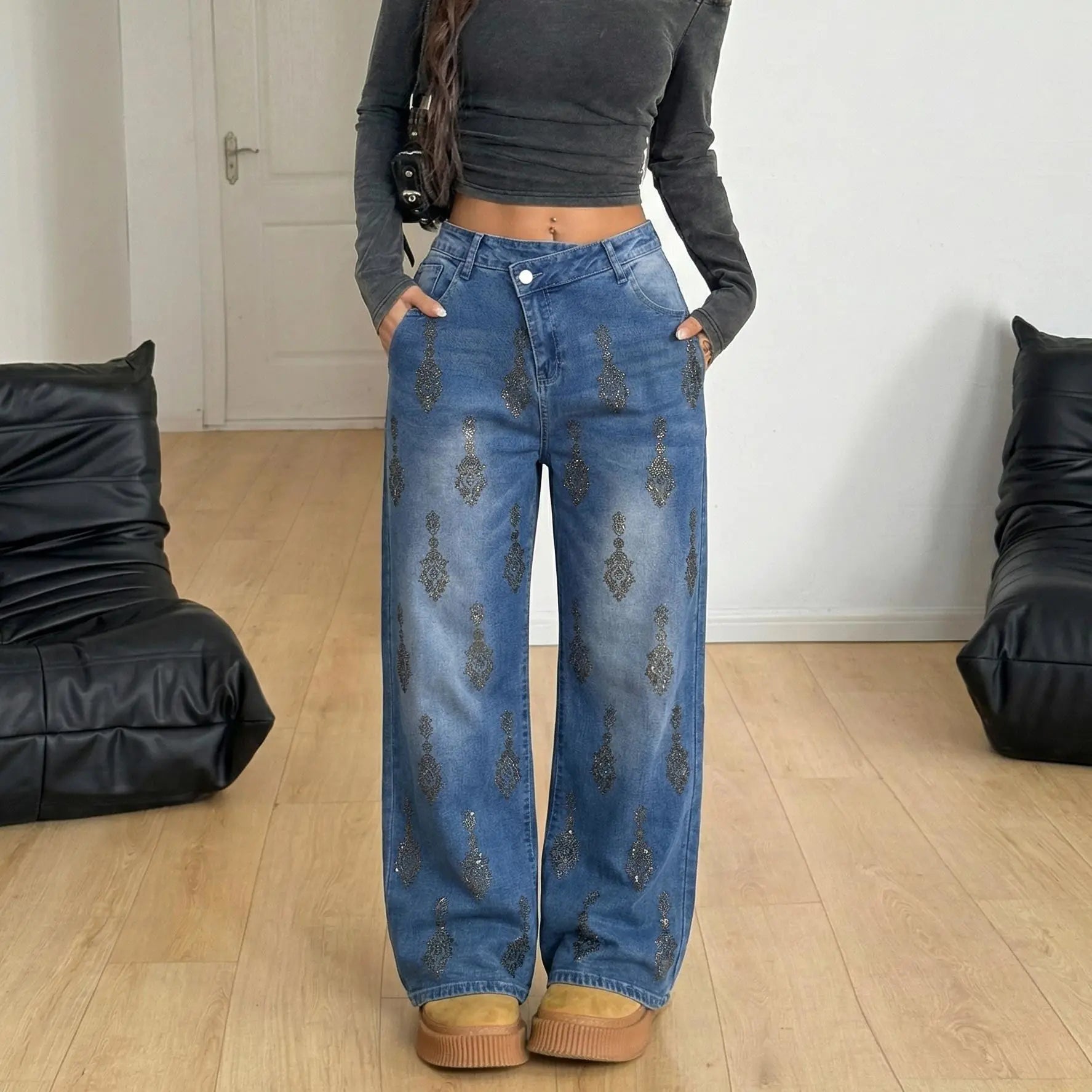 Person wearing blue jeans with decorative patterns in a room with black bean bags. TCH Rhinestone Pendant Allover Denim Jeans