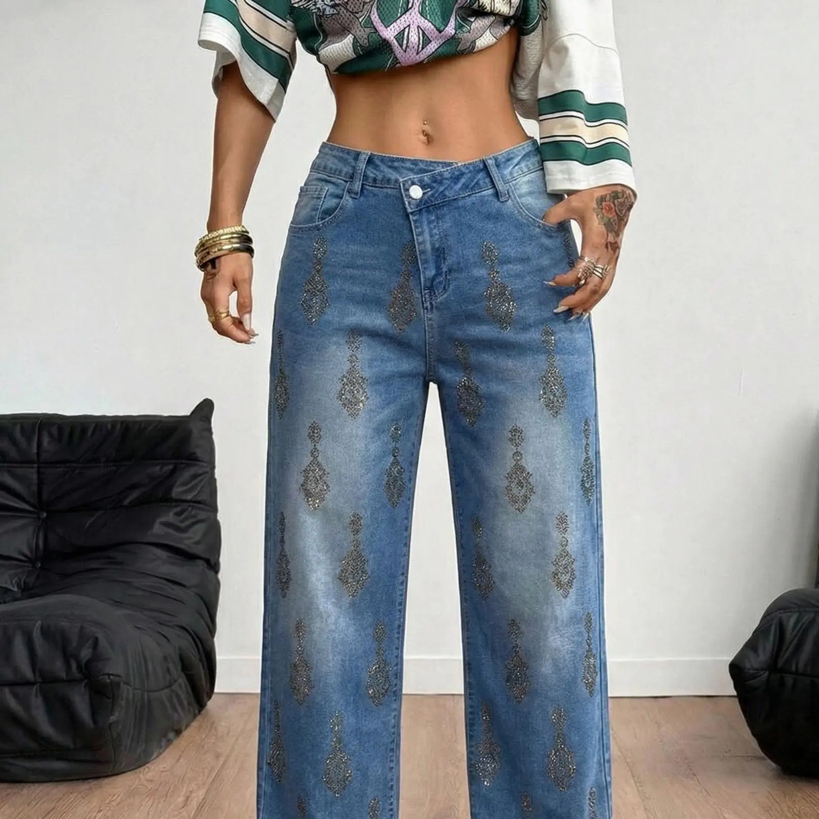 Person wearing blue jeans with decorative patterns in a casual setting. TCH Rhinestone Pendant Allover Denim Jeans