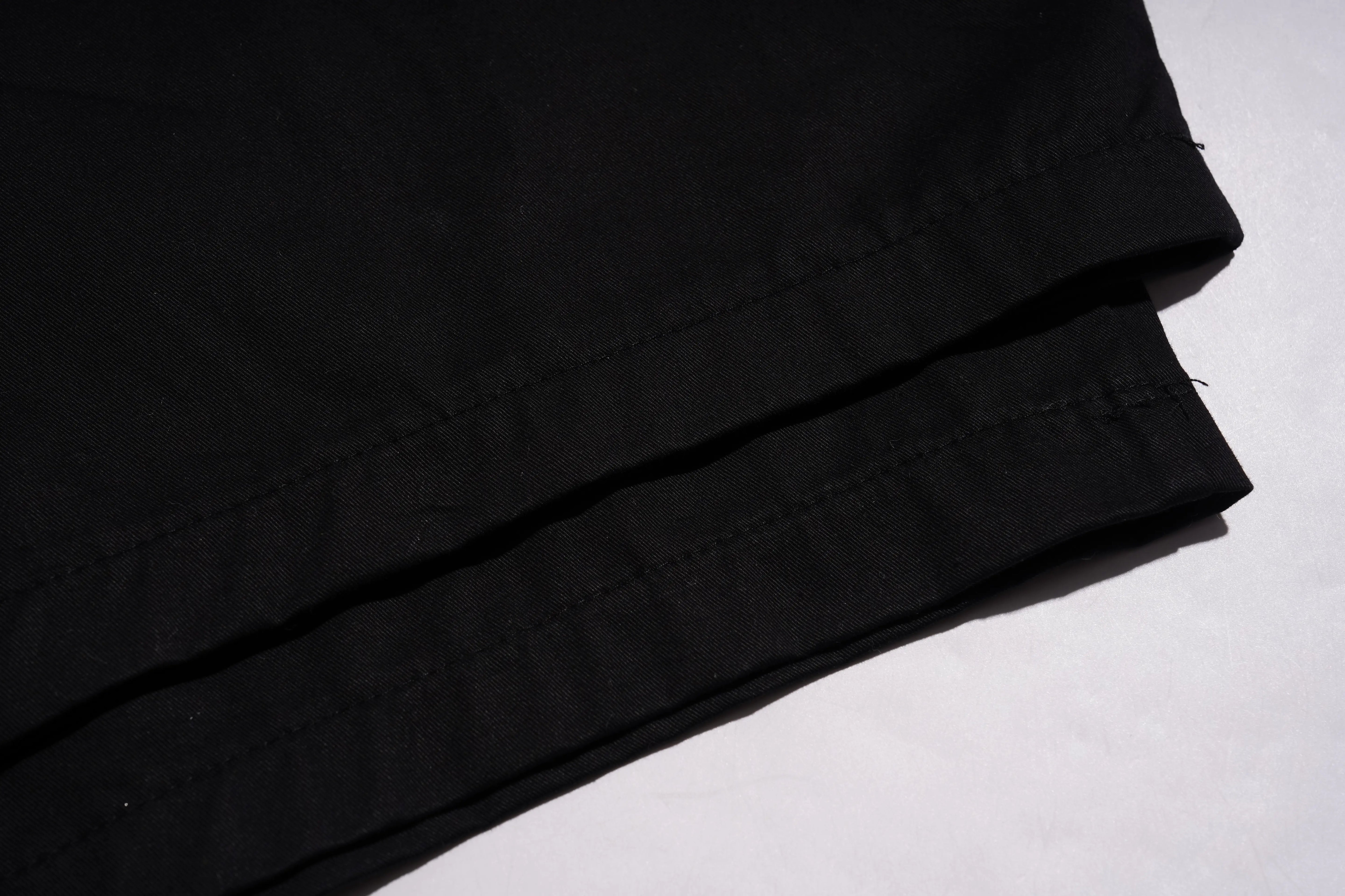 Close-up of folded black fabric with visible stitching on a white background. TCH Rhinestone Phoenix Cargo Wide-Leg Pants