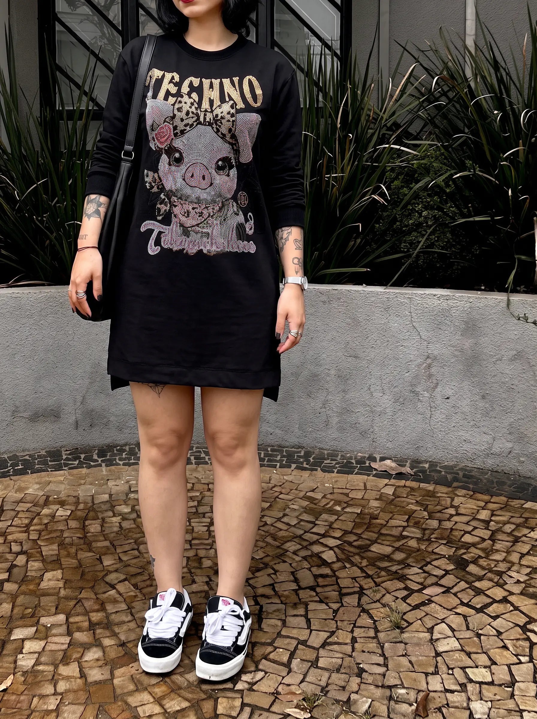 A person wearing a black long-sleeve Techno brand graphic t-shirt dress featuring a pink pig illustration, paired with black and white sneakers, standing outdoors on a mosaic stone floor. TCH Rhinestone Pig Graphic Long Sweatshirt Dress