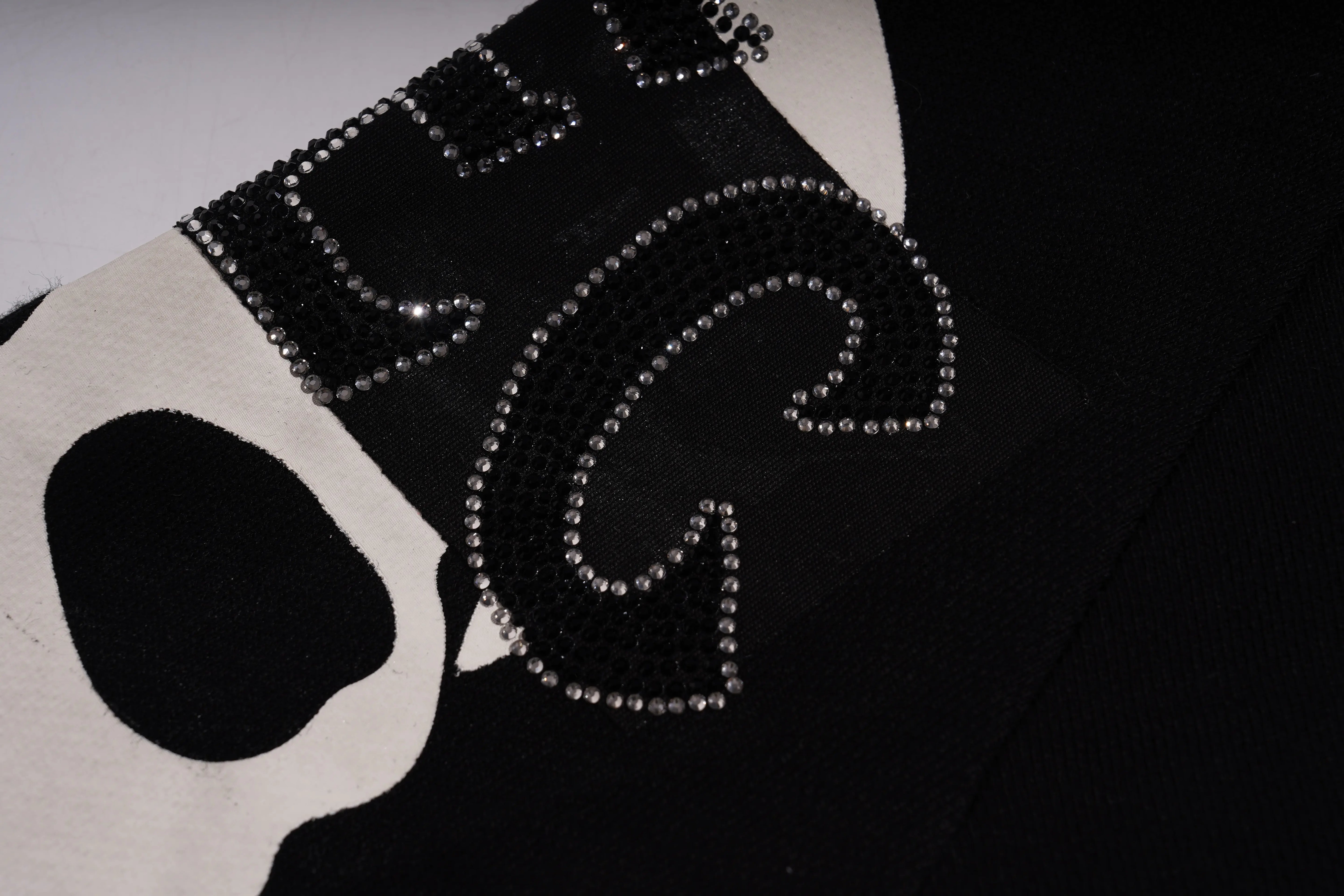 Black and white patterned fabric with decorative elements on a dark background, TCH Rhinestone Pink Bear Skull Sleeve Sweatshirt