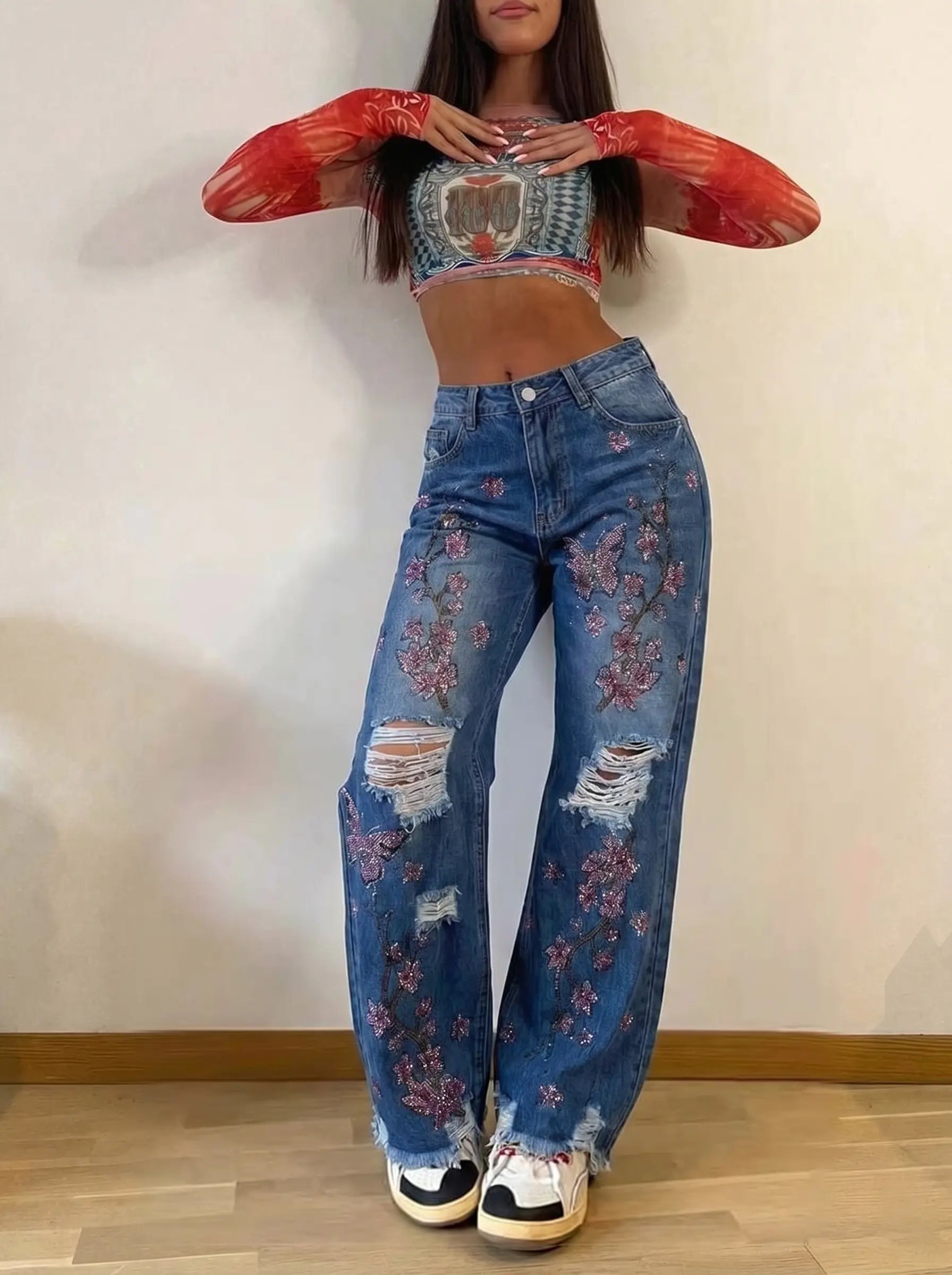 Person wearing a red sheer top and blue jeans with floral designs on a plain background, TCH Rhinestone Plum Blossom Tree Distressed Denim Jeans