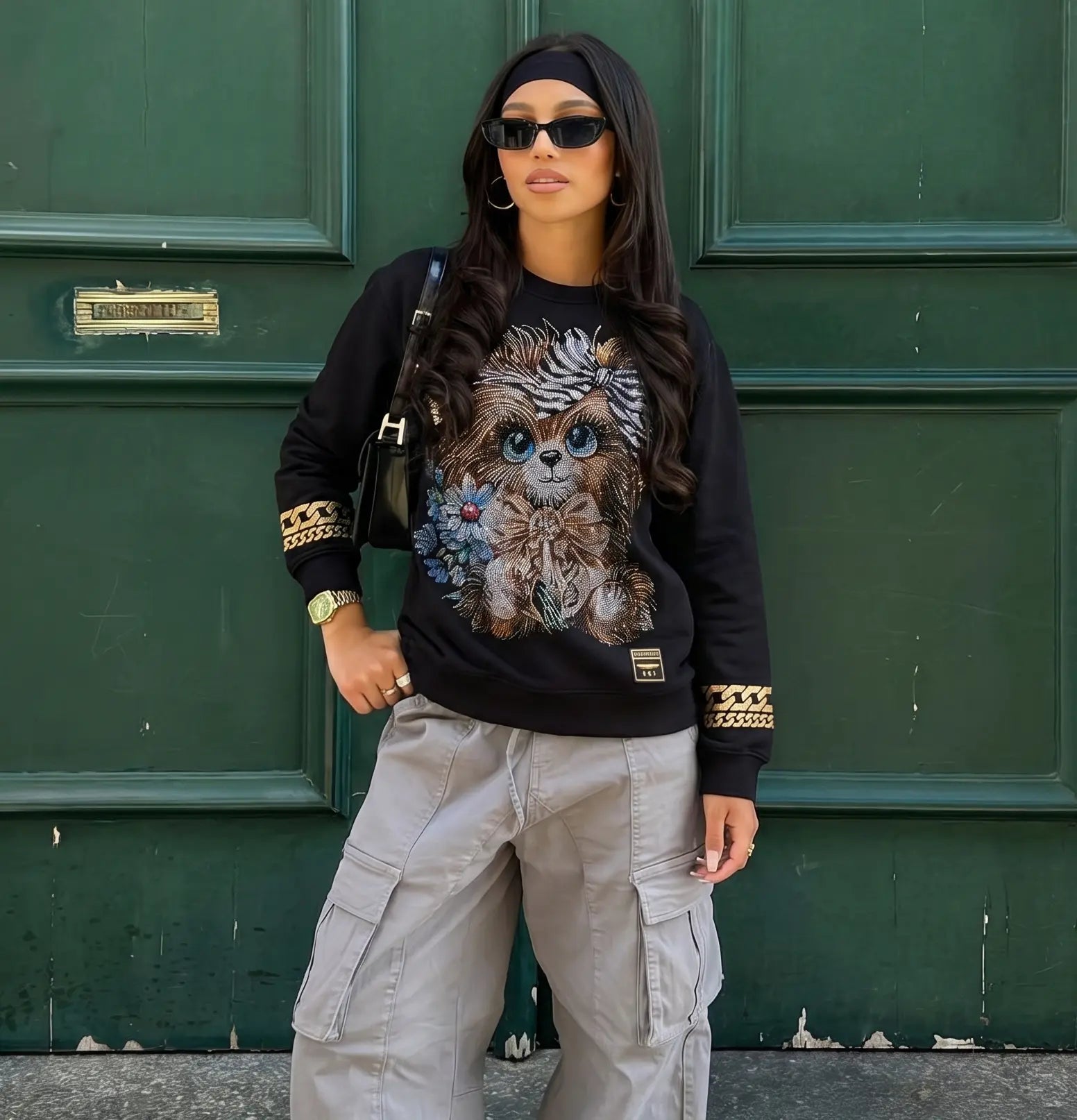 Person wearing a black sweatshirt with a graphic design and beige cargo pants against a green door. TCH Rhinestone Puppy Black Streetwear Sweatshirt