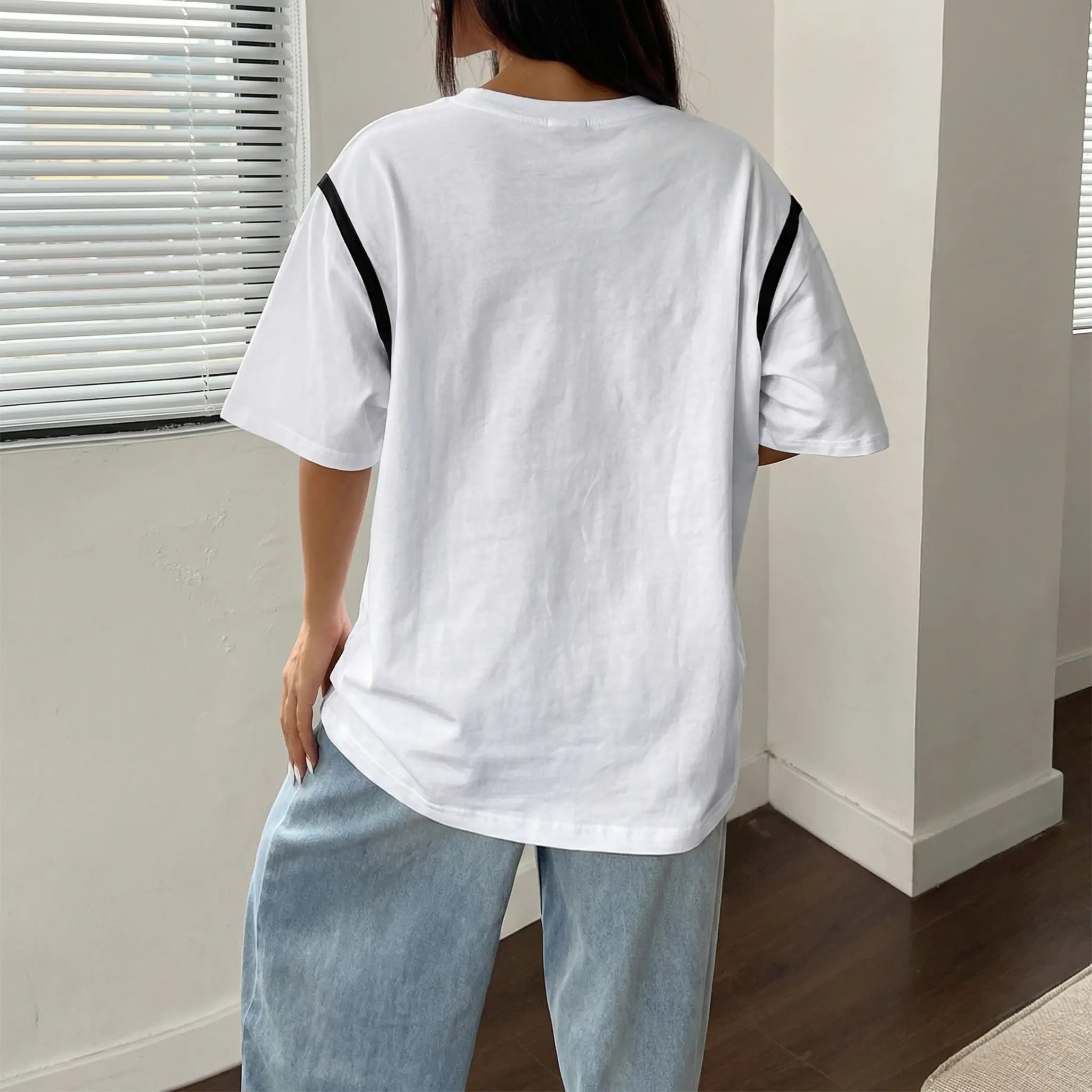 Person wearing a white t-shirt with black stripes on the sleeves and light blue pants indoors. TCH Rhinestone Puppy Bow White T-Shirt-1 8