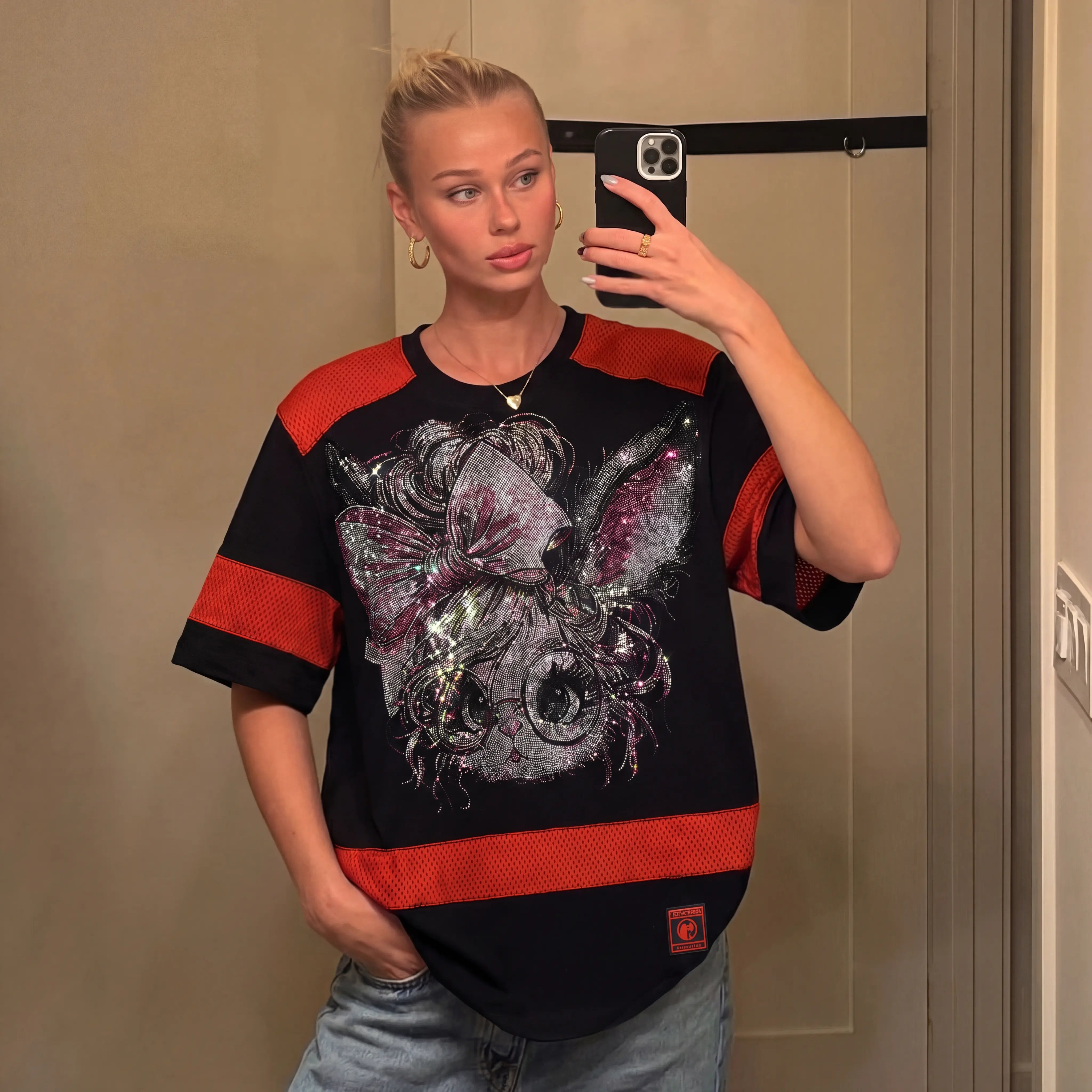 Person wearing a black and red shirt with a unique design, taking a mirror selfie. TCH Rhinestone Rabbit Black Red Jersey