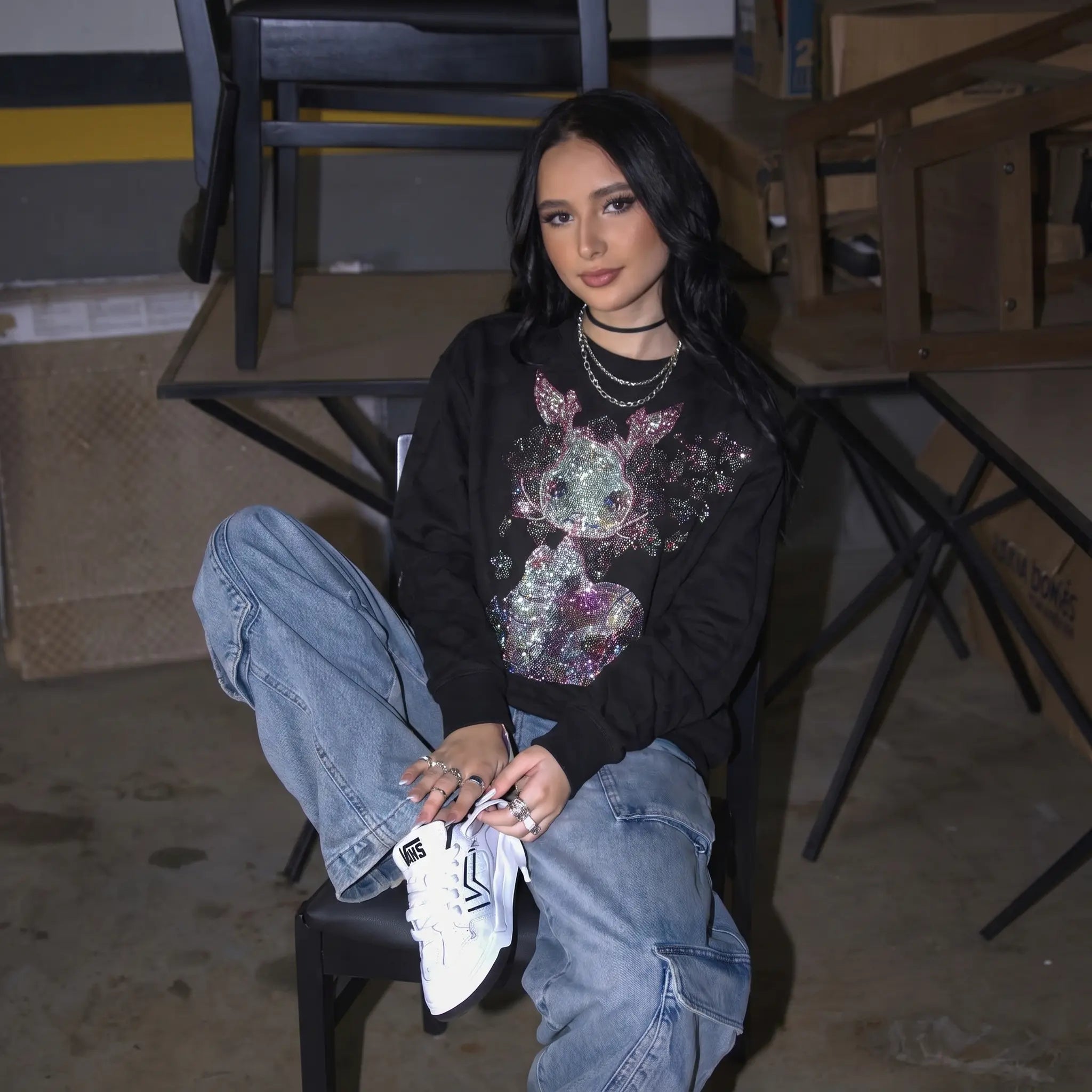 Woman sitting on a chair in an indoor setting with furniture and boxes in the background, TCH Rhinestone Snake Black Crewneck Sweatshirt