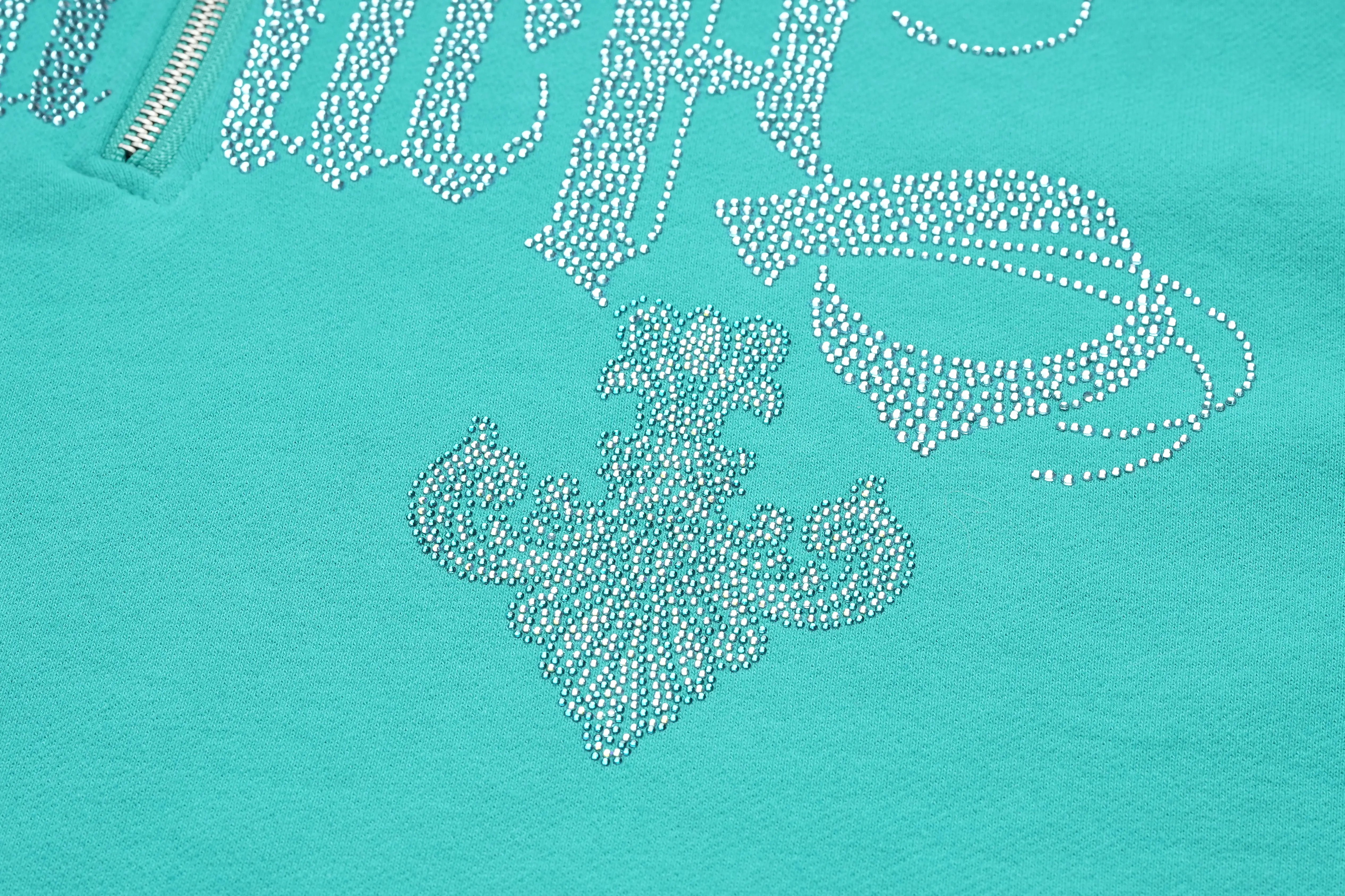 Turquoise hoodie with rhinestone embellishments on a turquoise background, TCH Rhinestone “Tchmuch” Logo & Wings Teal Zip Tracksuit Set