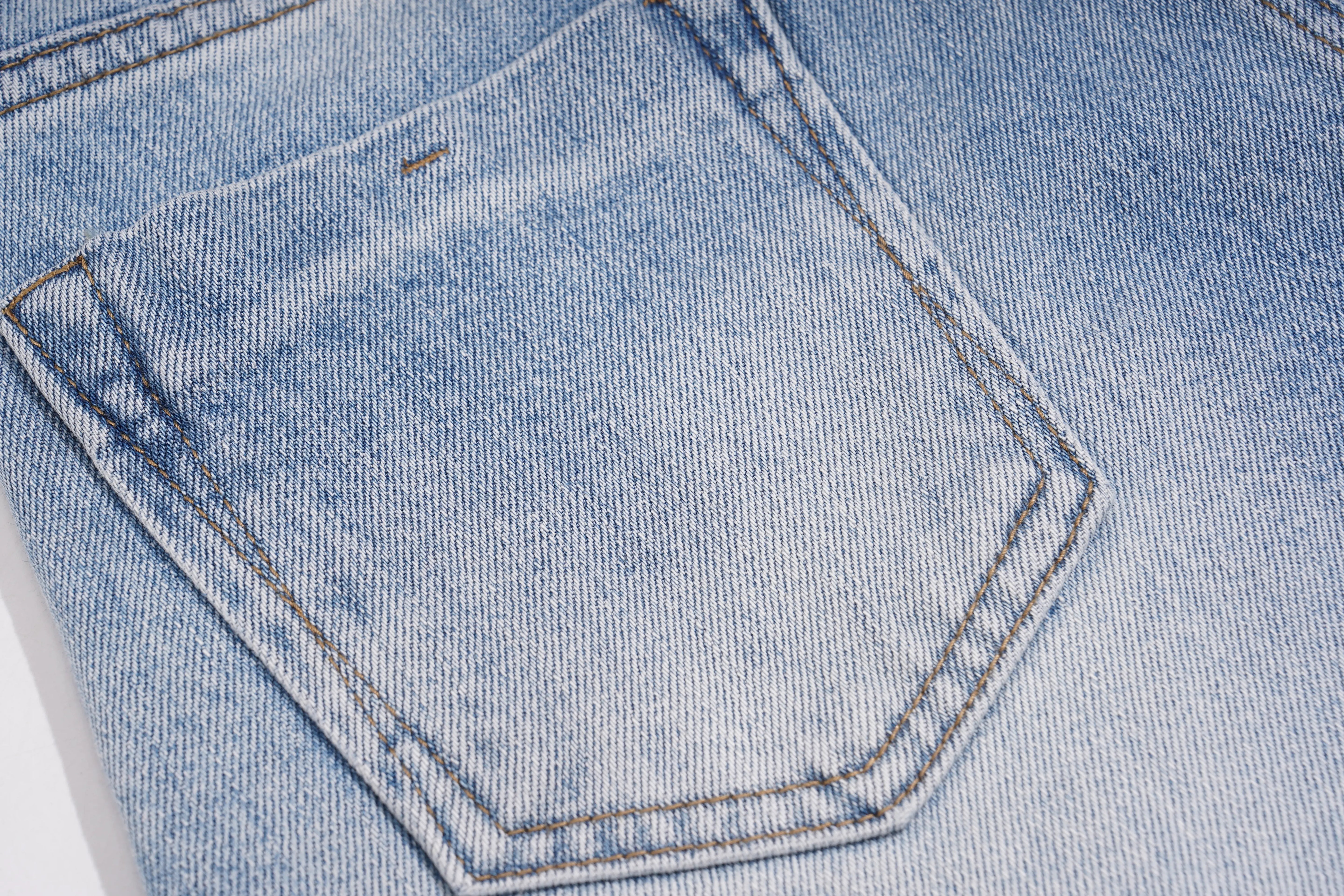 Close-up of a light blue denim pocket with contrast brown stitching, showing the detailed twill texture of the fabric. TCH Rhinestone Teddy Bear Bow Denim Shorts