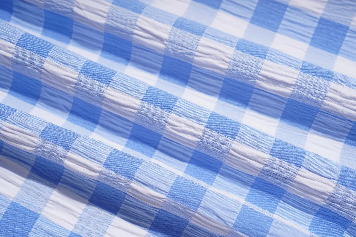 A close-up of a crinkled blue and white checkered fabric, showing the texture and pattern details. TCH Rhinestone Teddy Bear Bow Gingham Wide-Leg Pants