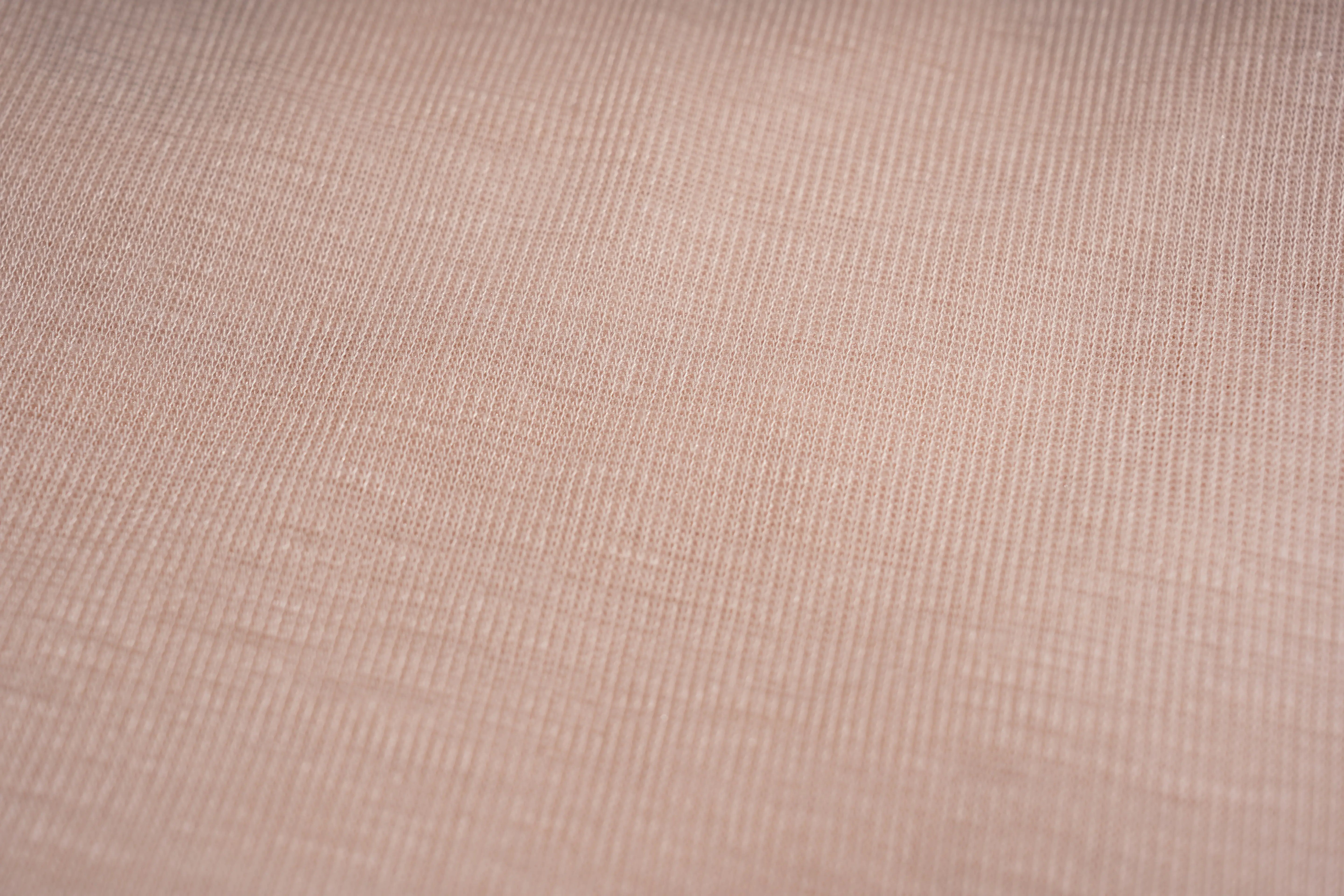 A close-up of a textured fabric with a fine ribbed pattern in a warm, dusty rose or mauve pink color. TCH Rhinestone Teddy Bear Bow Ruffle Long Sleeve Top