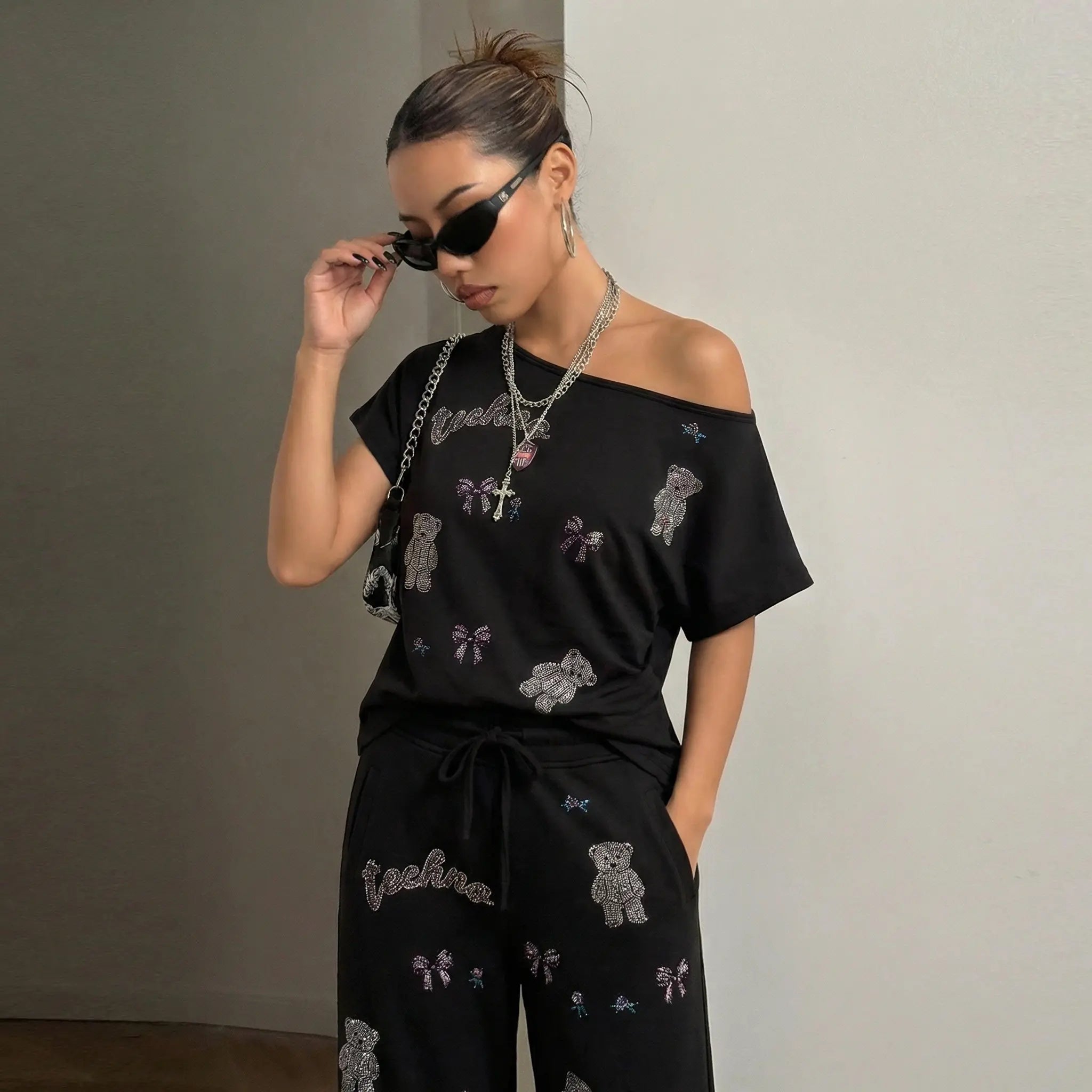 Woman wearing a black off-shoulder top and pants with teddy bear patterns against a plain background, TCH Rhinestone Teddy Bear & Bow Set