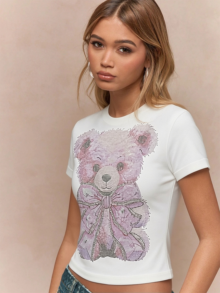 Front view of a woman wearing the TCH Urban Rhinestone Teddy Bear Graphic Tee in white with distressed denim.