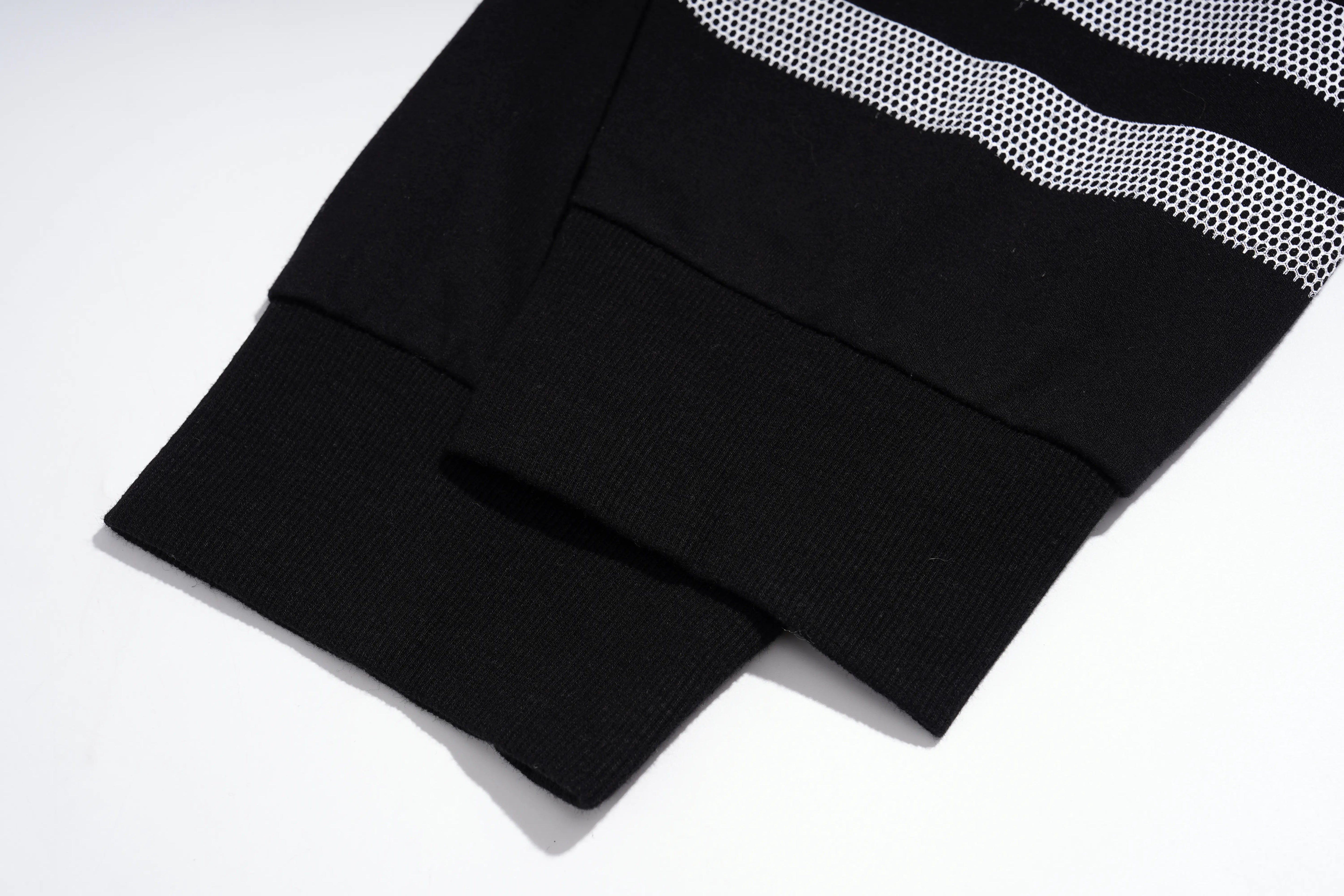 Close-up of black knit fabric with a wide white and black mesh stripe detail, shown on a white background. TCH Rhinestone Teddy Bear Graphic Black Jogger Pants