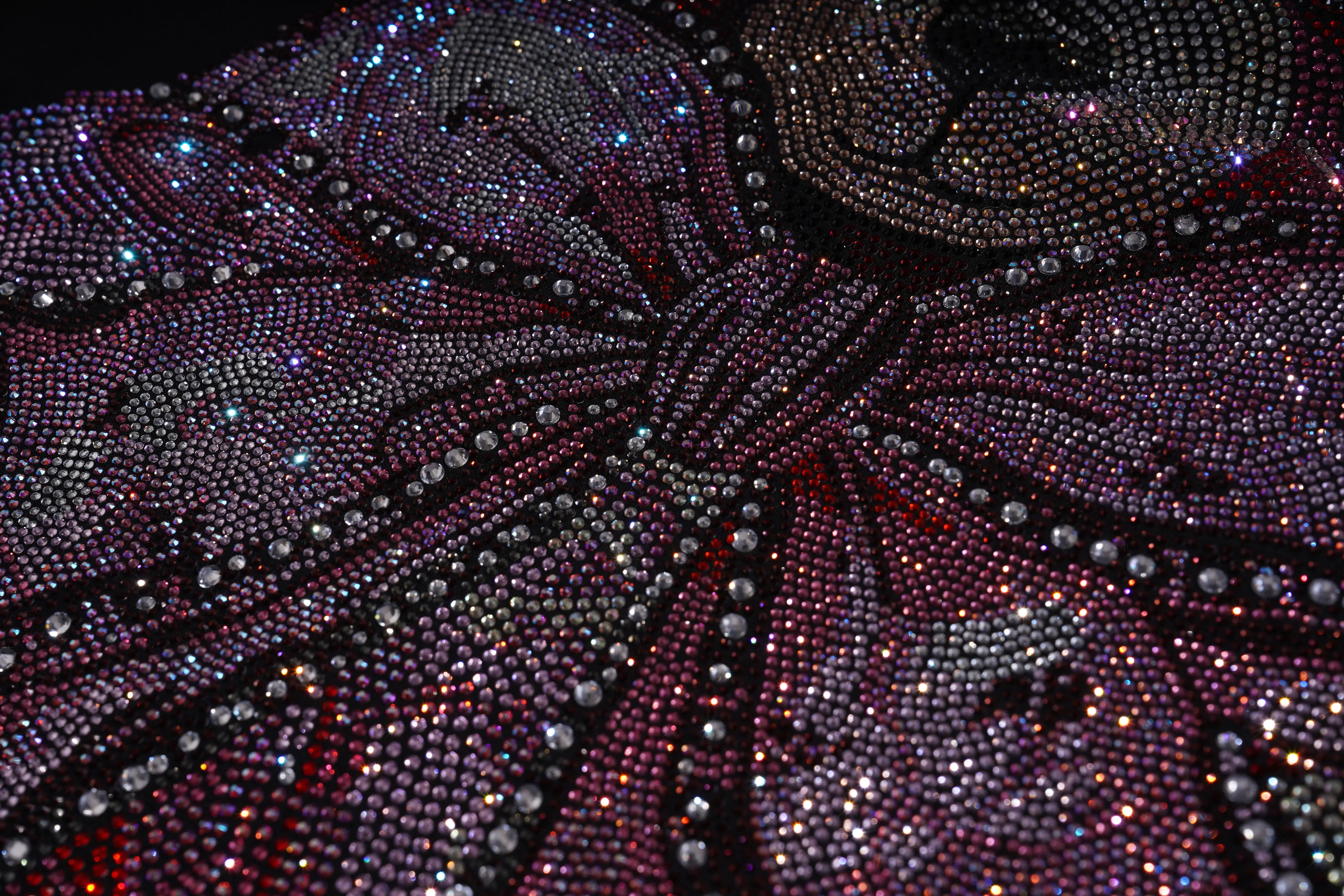 Close-up of a butterfly-shaped object covered in rhinestones on a dark background