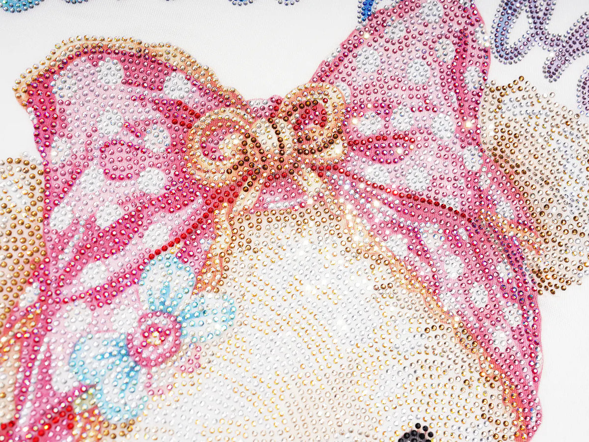 Close-up of a pink and white beaded bow design with gold-toned rhinestone outlines and small pastel blue floral accents on a white background. TCH Rhinestone Teddy Bear Graphic Striped Sleeve Long Sleeve Top
