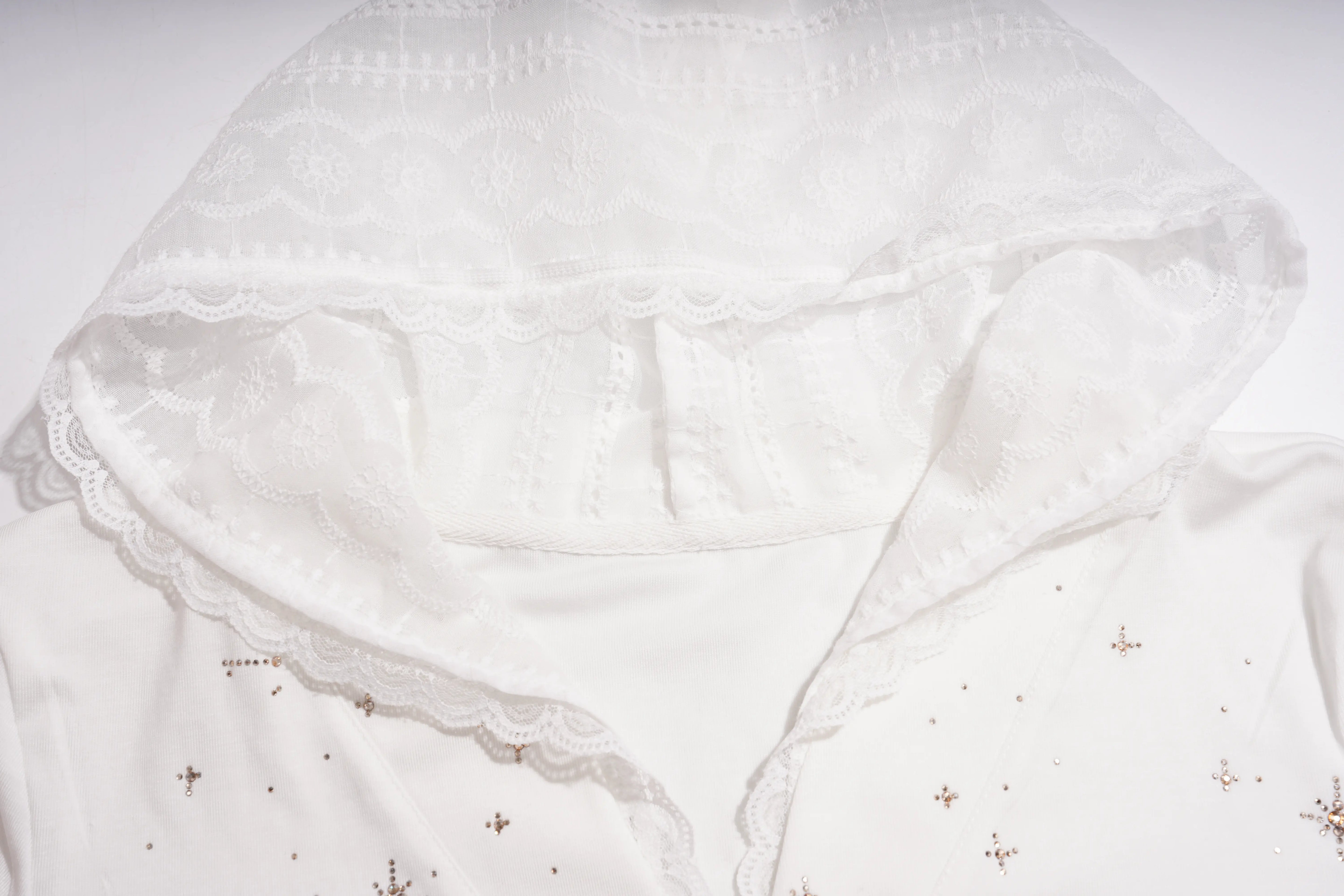 Close-up of a white hooded garment with delicate lace trim and small embroidered star details on a plain white background. TCH Rhinestone Teddy Bear Lace Hooded T-Shirt