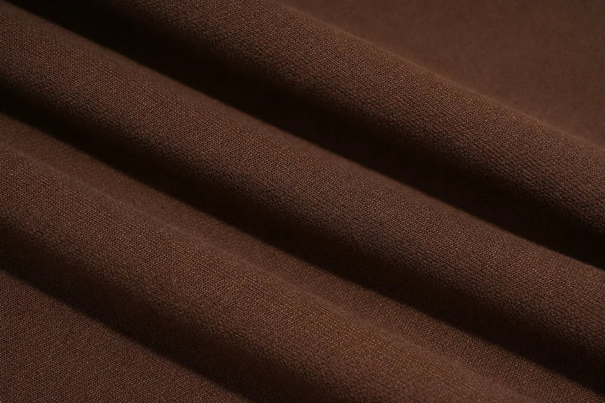 A close-up of draped brown fabric with soft folds showing a fine knit texture. TCH Rhinestone Teddy Bear Techno Sweatshirt Dress