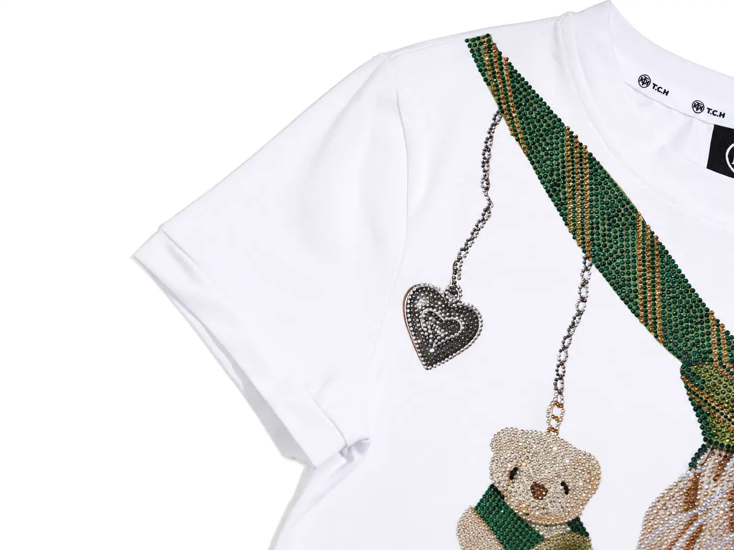 A white short-sleeve T-shirt with a beaded green and gold shoulder strap design, a heart-shaped rhinestone pendant, and a teddy bear embellishment on the front.T CH Rhinestone Teddy Bear Tie Graphic White T-Shirt