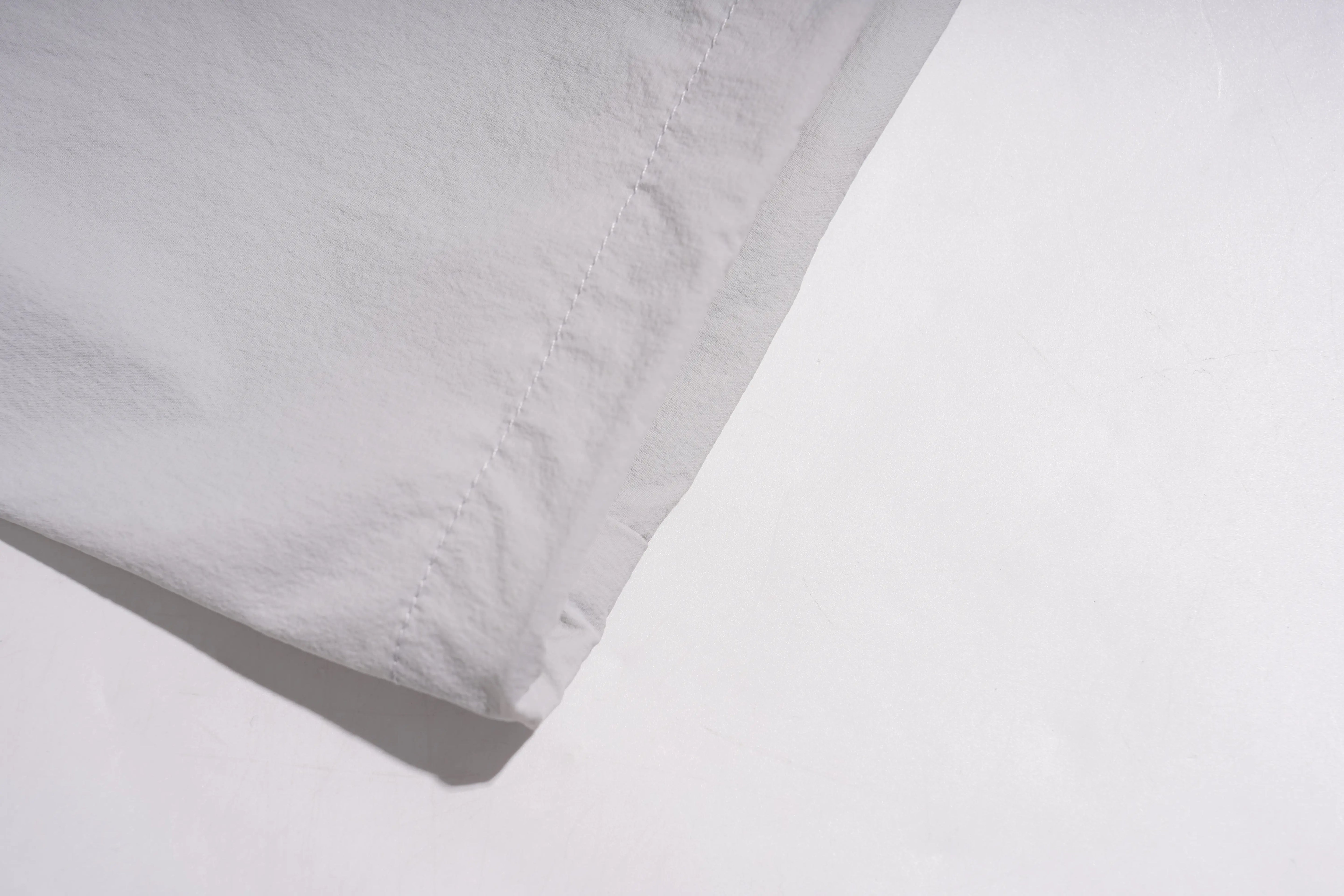 A close-up of a folded white fabric item, showing the texture and neat hem stitching on a white background. TCH Rhinestone Wing Active 3-Piece Tracksuit Set