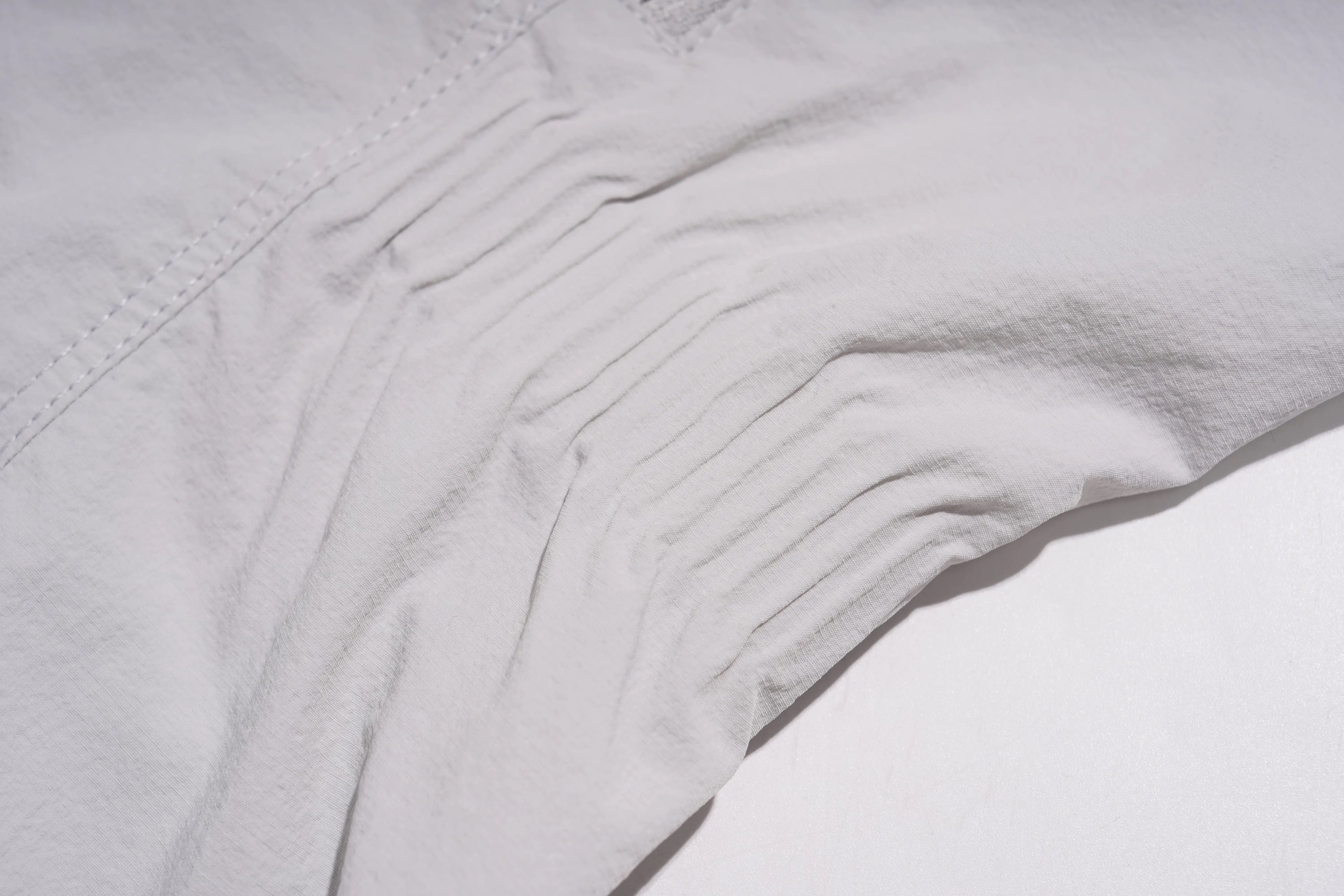 A close-up of light gray fabric with a gathered, pleated texture and visible stitching along the edge. TCH Rhinestone Wing Active 3-Piece Tracksuit Set