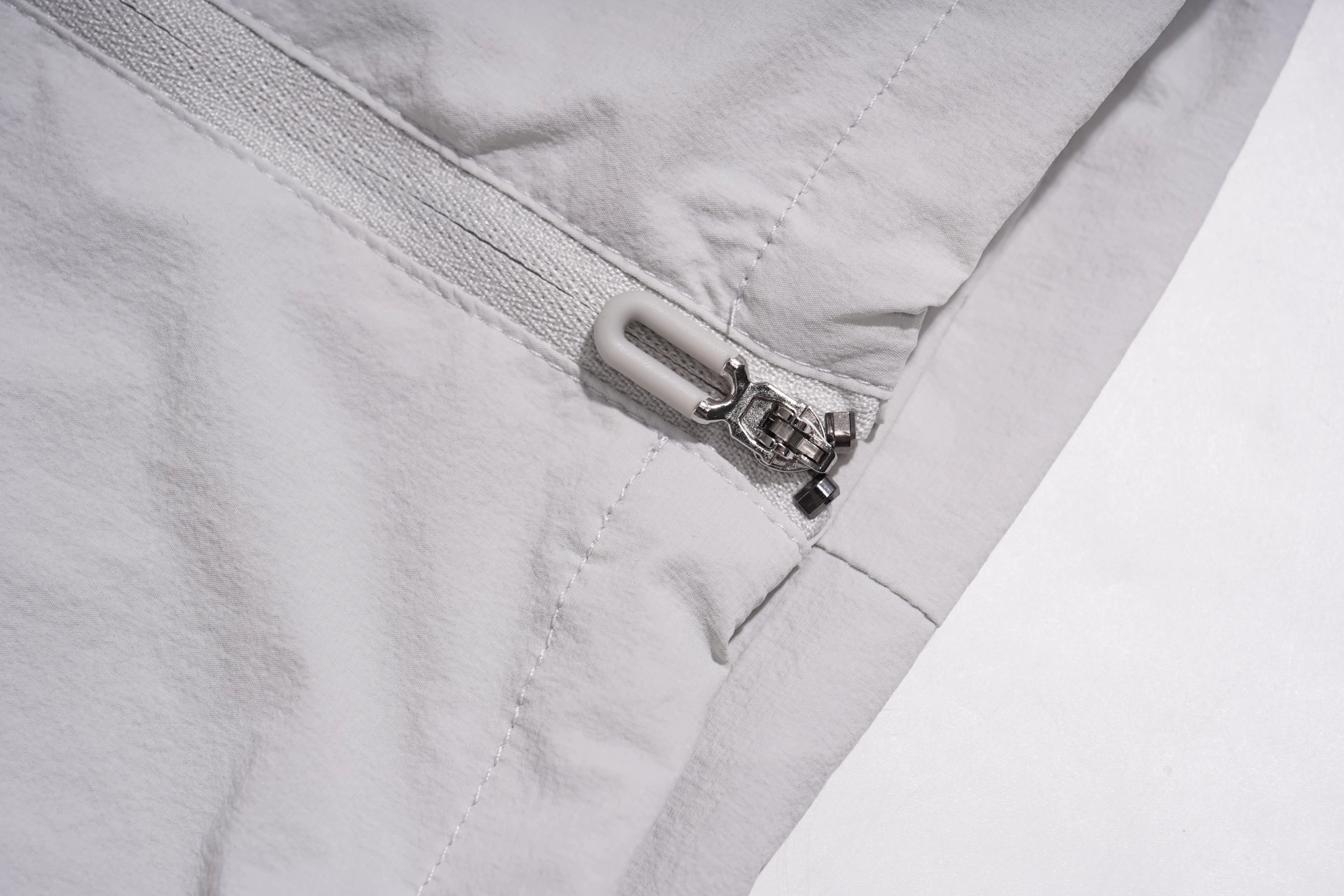 Close-up of a light gray fabric garment with a silver zipper and a small metal clip detail. TCH Rhinestone Wing Active 3-Piece Tracksuit Set