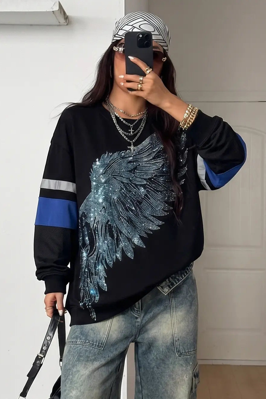 Person wearing a black sweater with a blue and white design, taking a mirror selfie. TCH Rhinestone Wing Black Crewneck Sweatshirt